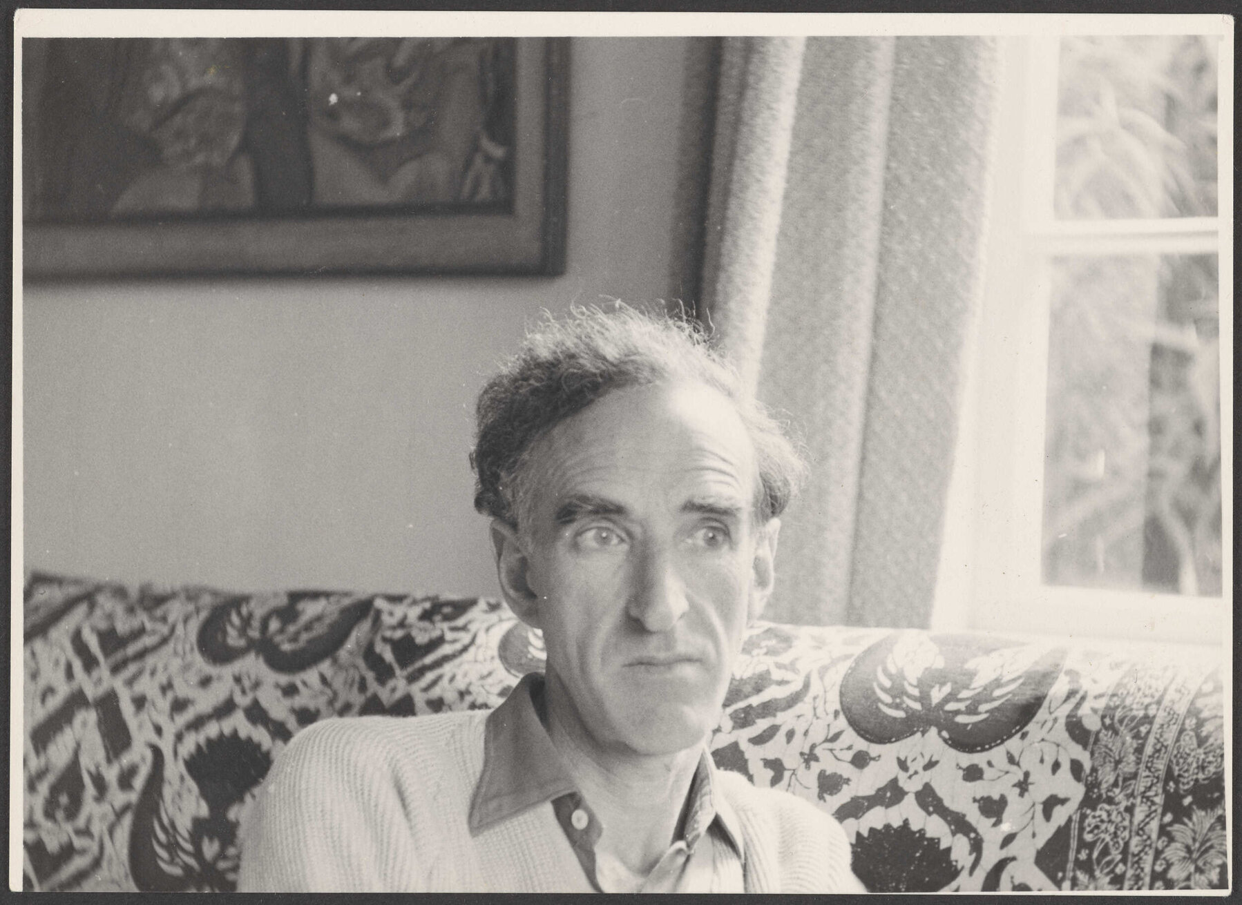 Charles Brasch sitting on a couch