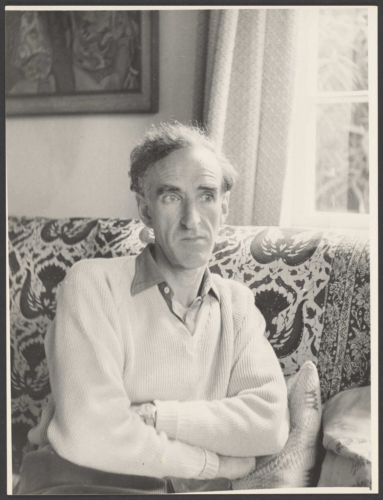 Charles Brasch sitting on a couch