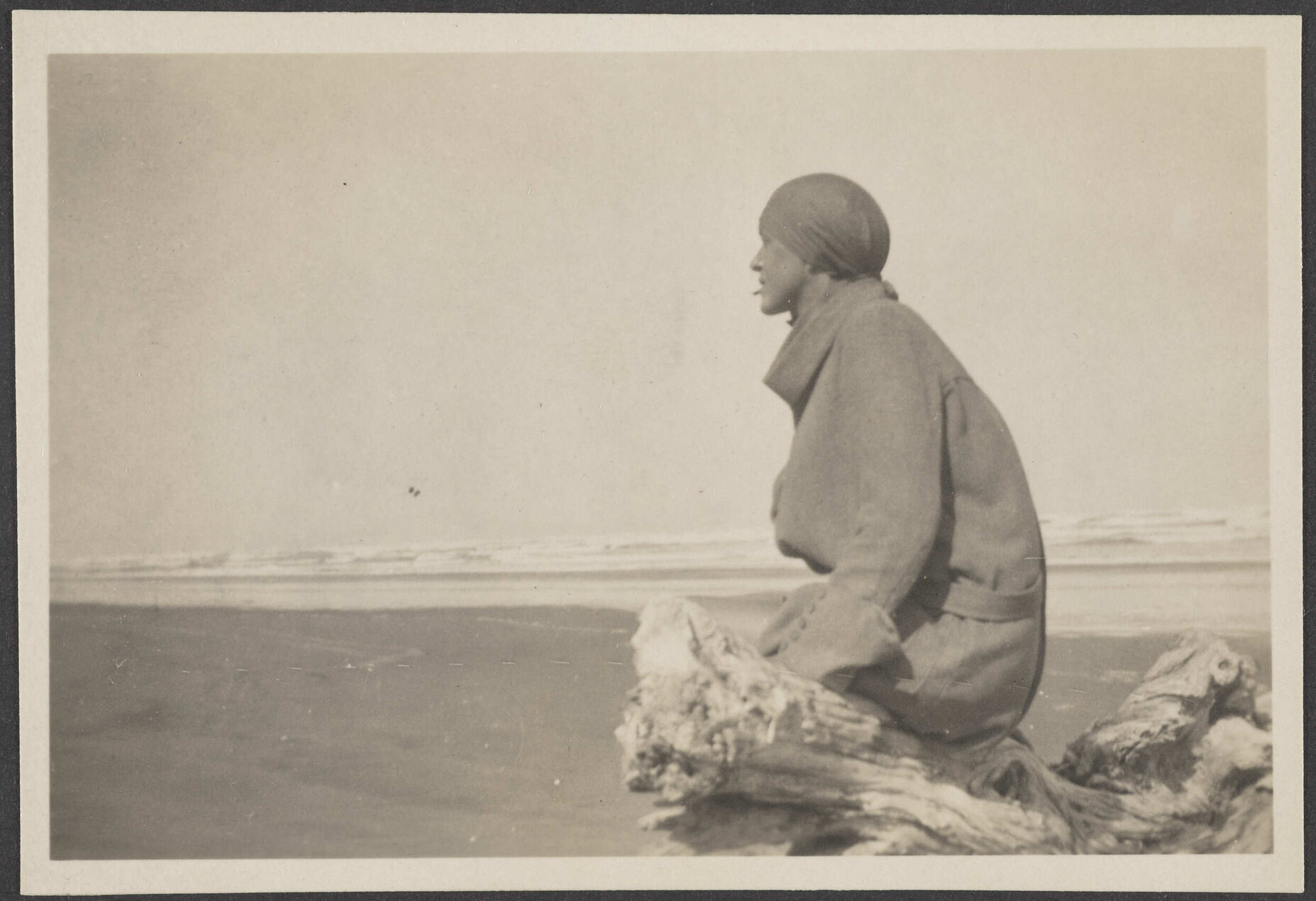 Person sitting on a log on the beach
