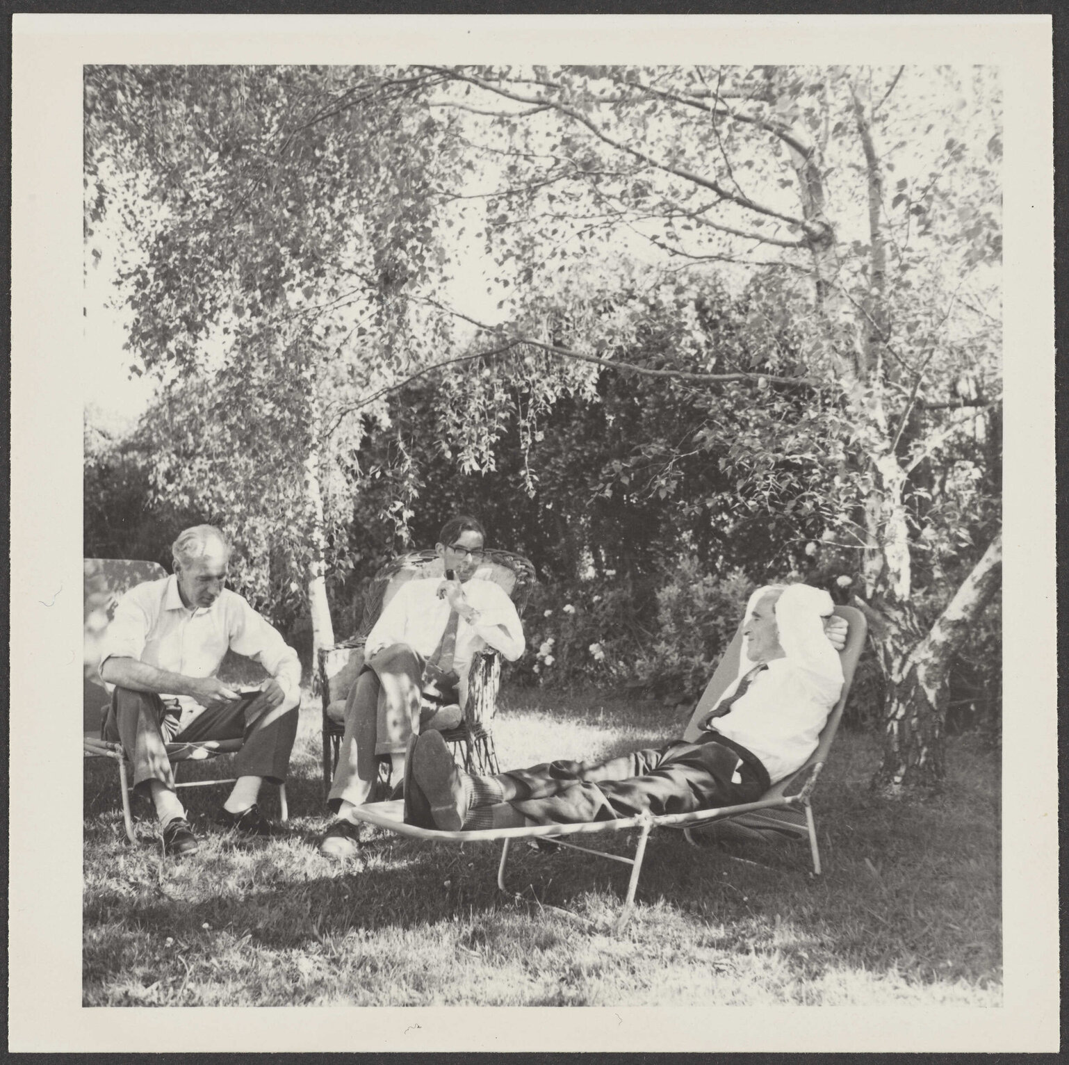 Charles Brasch, James Bertram and W.H. Oliver sitting under a tree