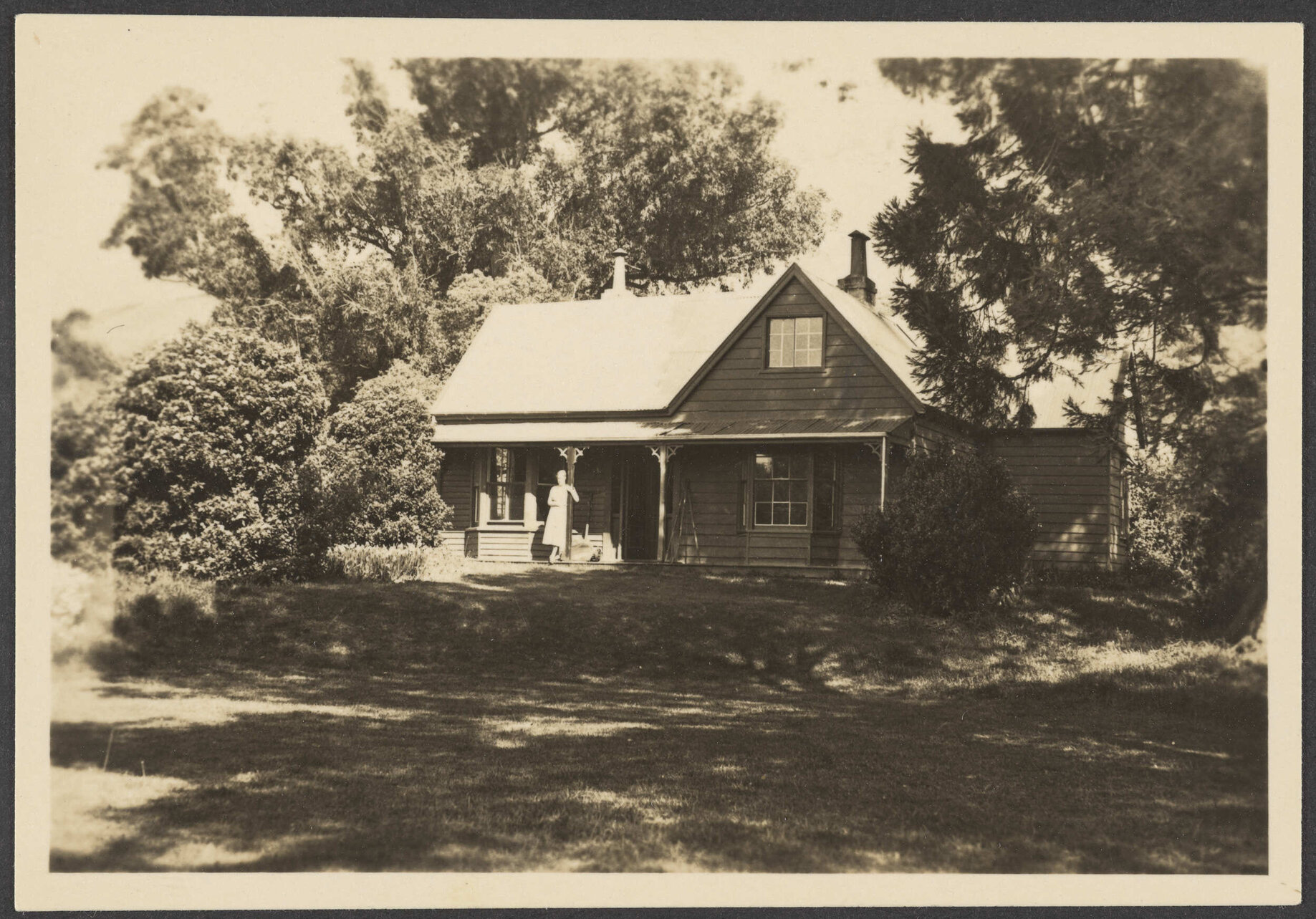 House among trees with woman on verandah