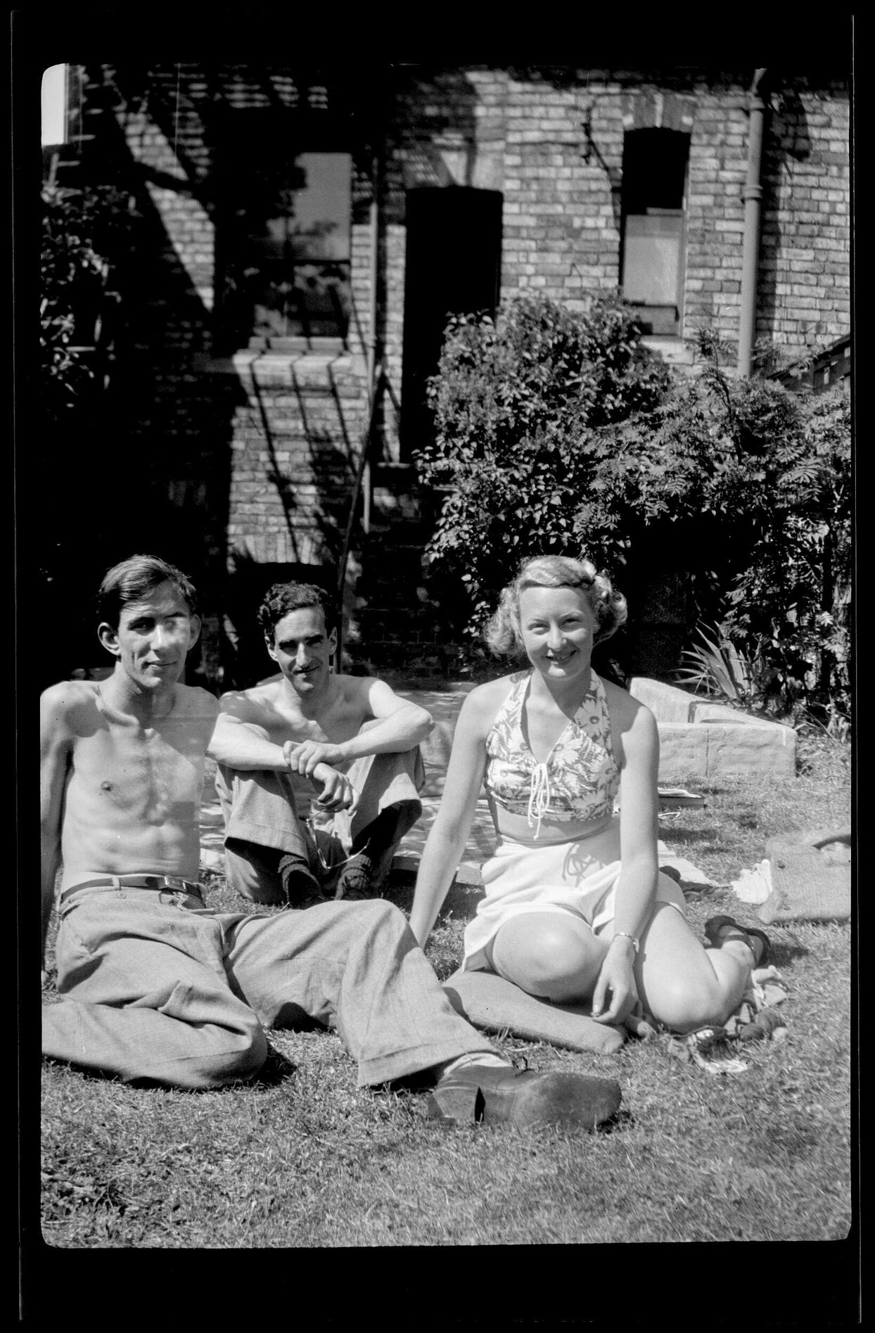 Three people sitting on grass