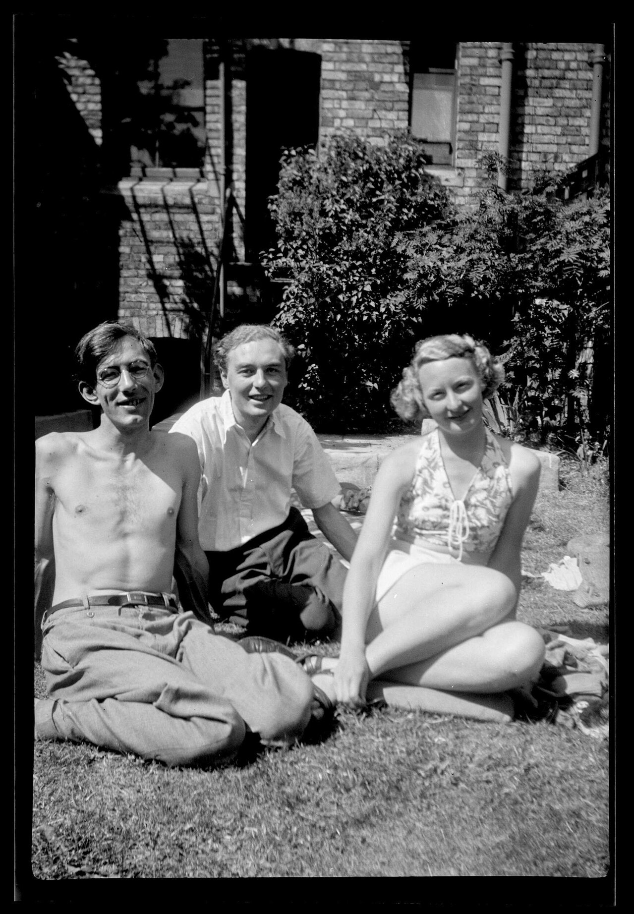 Three people sitting on grass