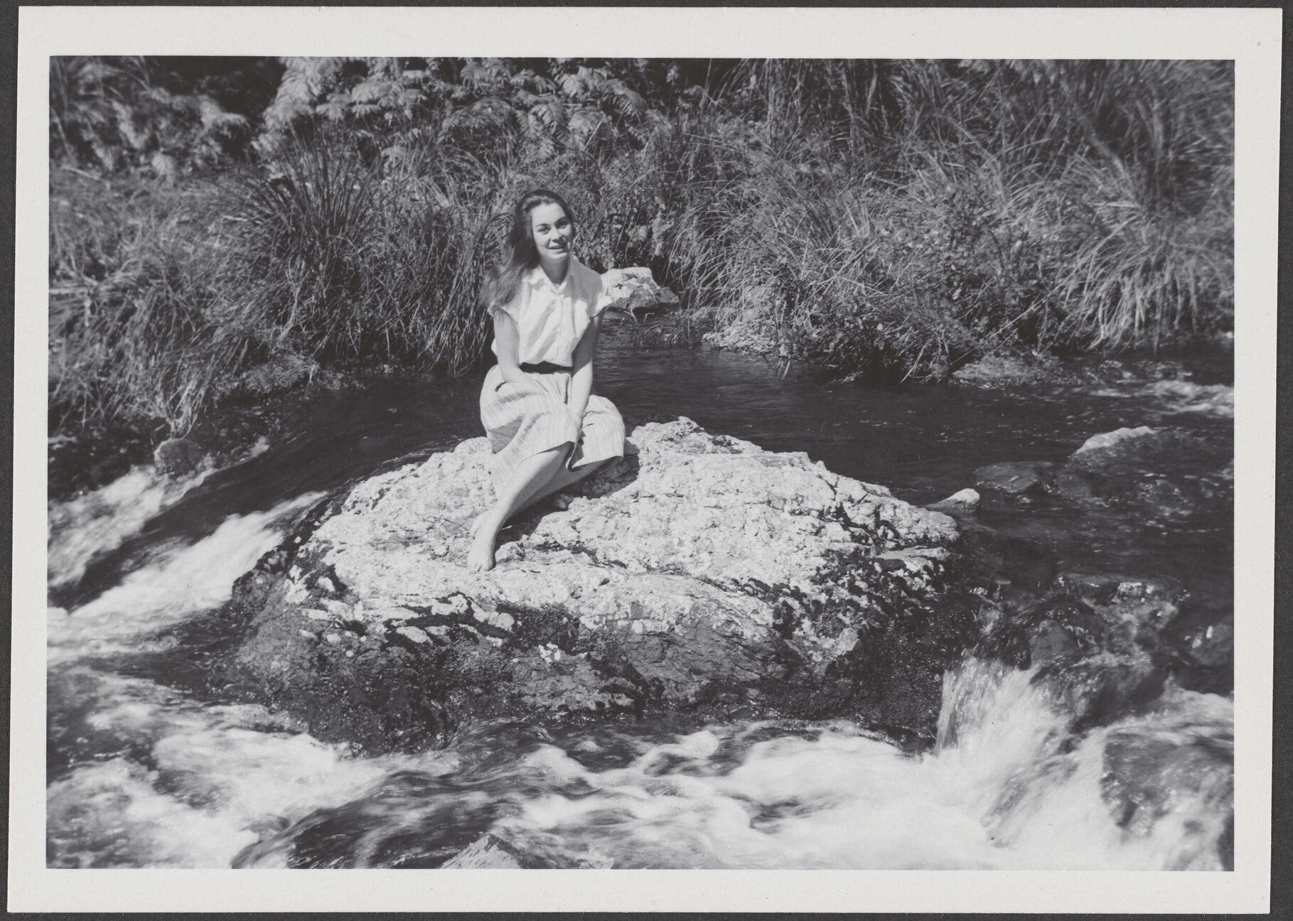 [? Garland] sitting on a rock in a river