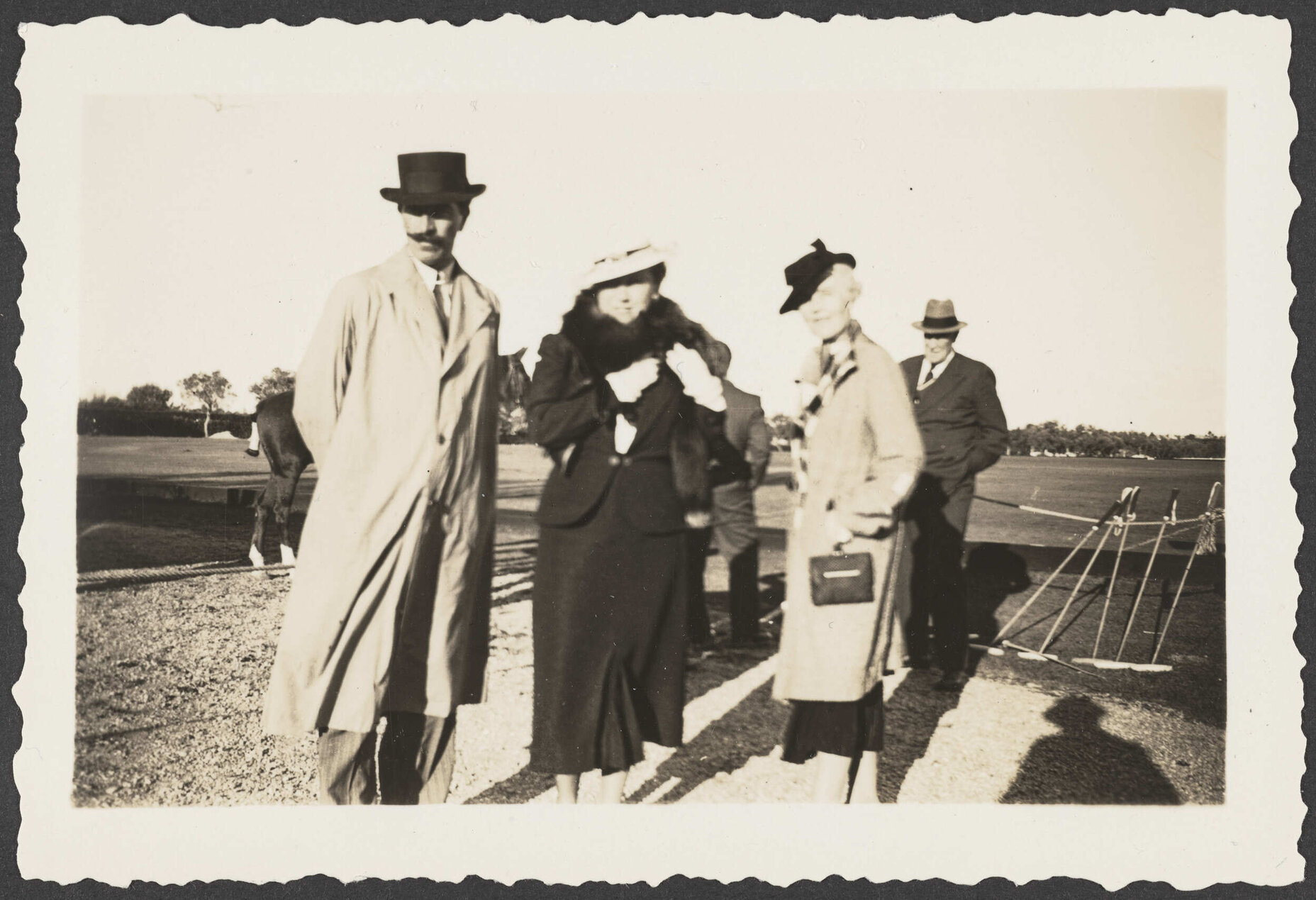 Group of people in field with polo mallets on right