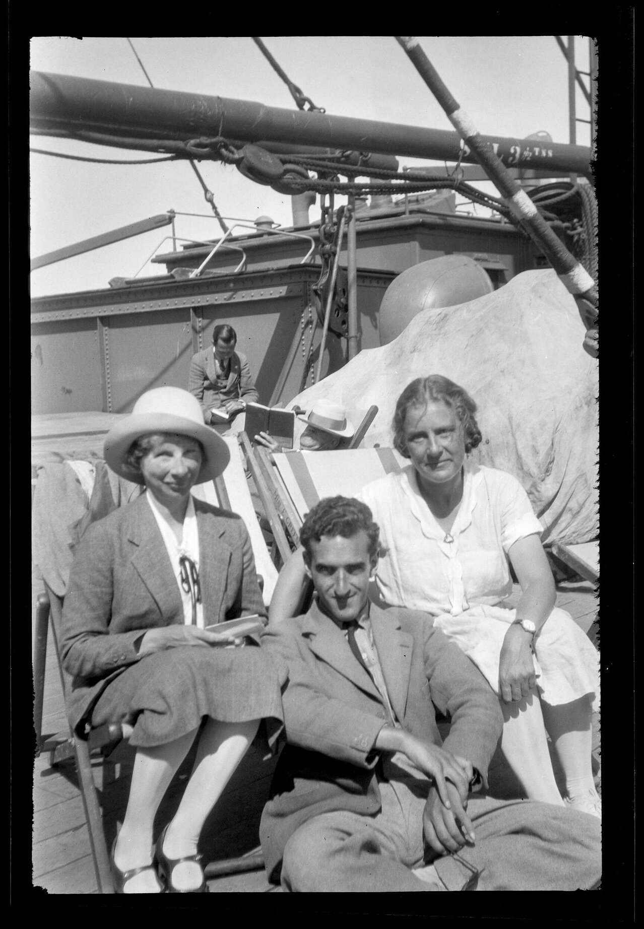 Charles Brasch and two women sitting on the deck of a ship