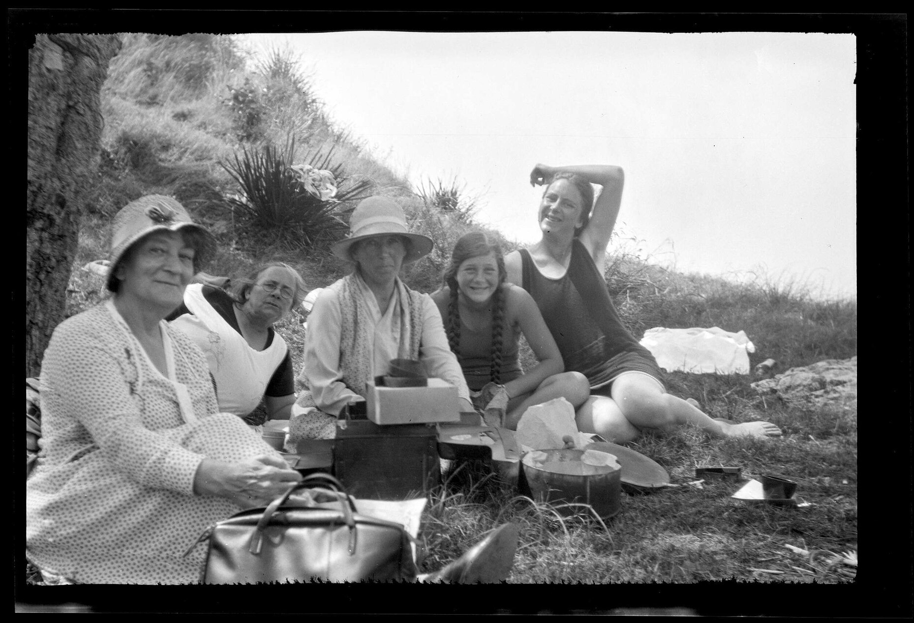 Five women and girls sitting on the ground outdoors