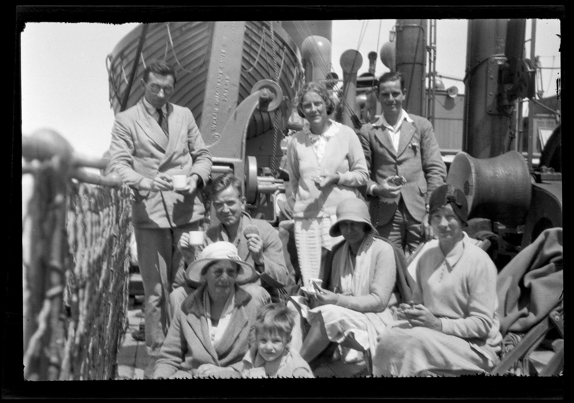 Eight people on the deck of the Barrabool, some holding food and drink