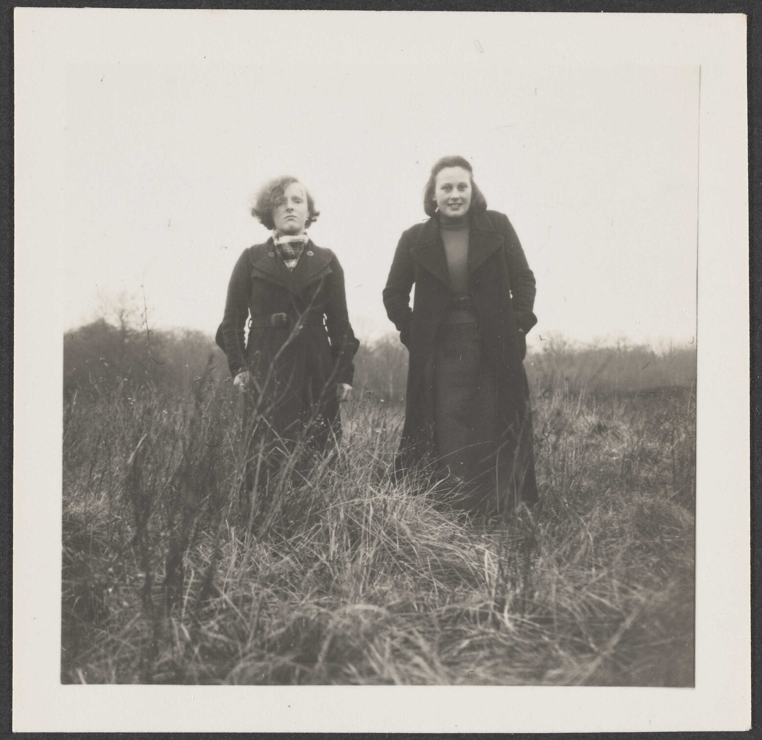 Two girls standing in long grass [Edna and Connie]