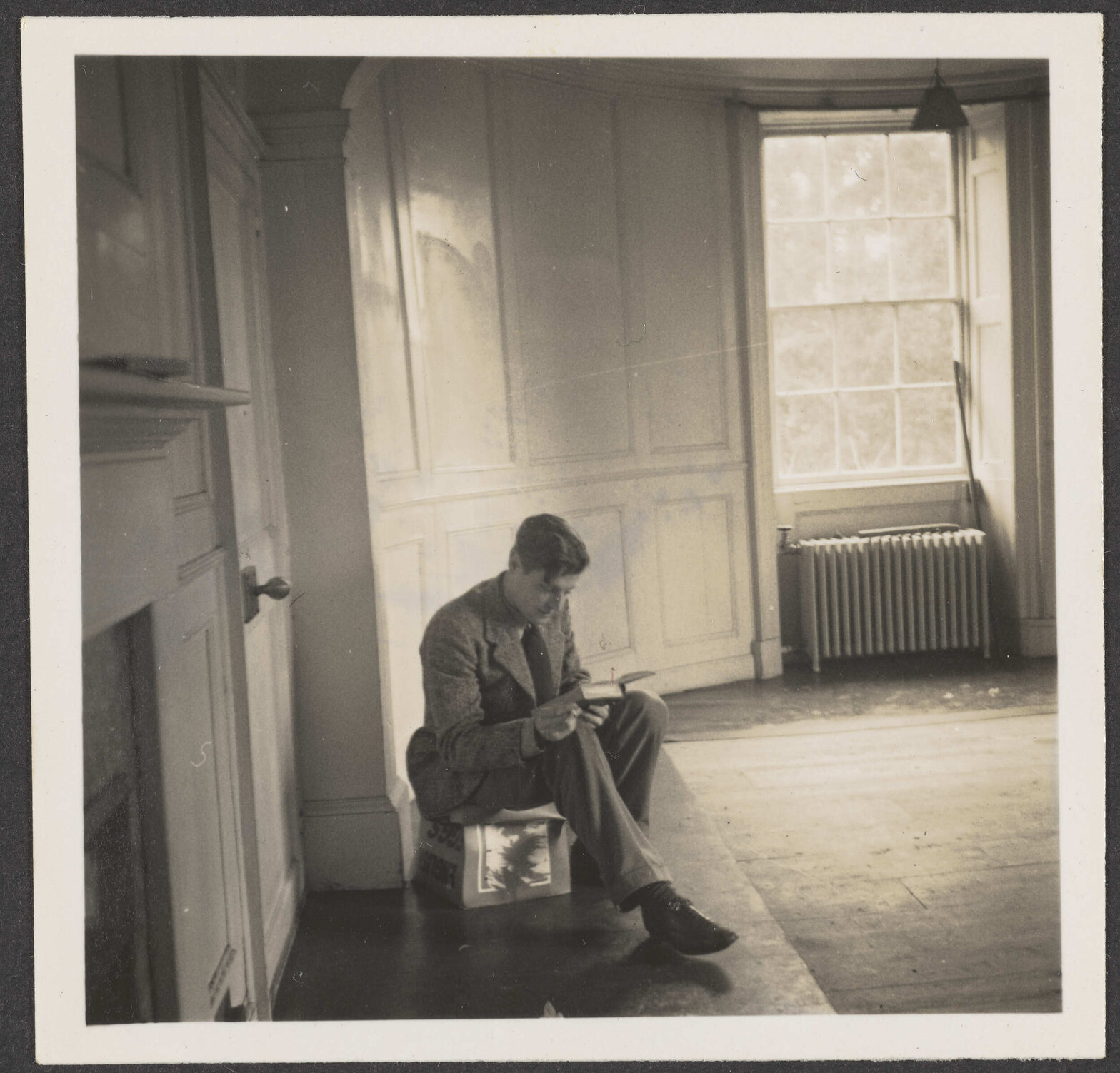 Man reading a book in an unfurnished room [Roger Cox]