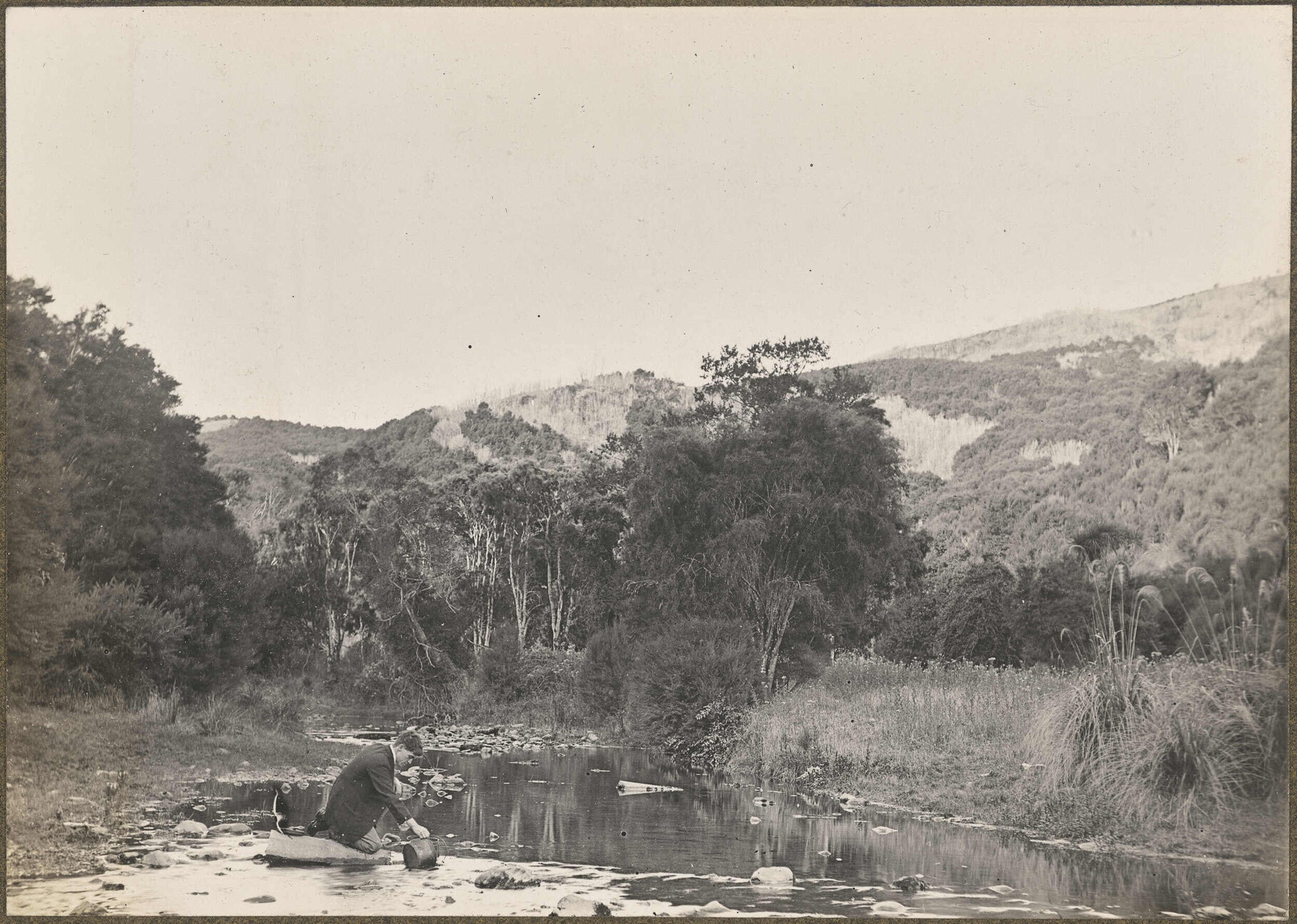 Unidentified man collecting water from a river