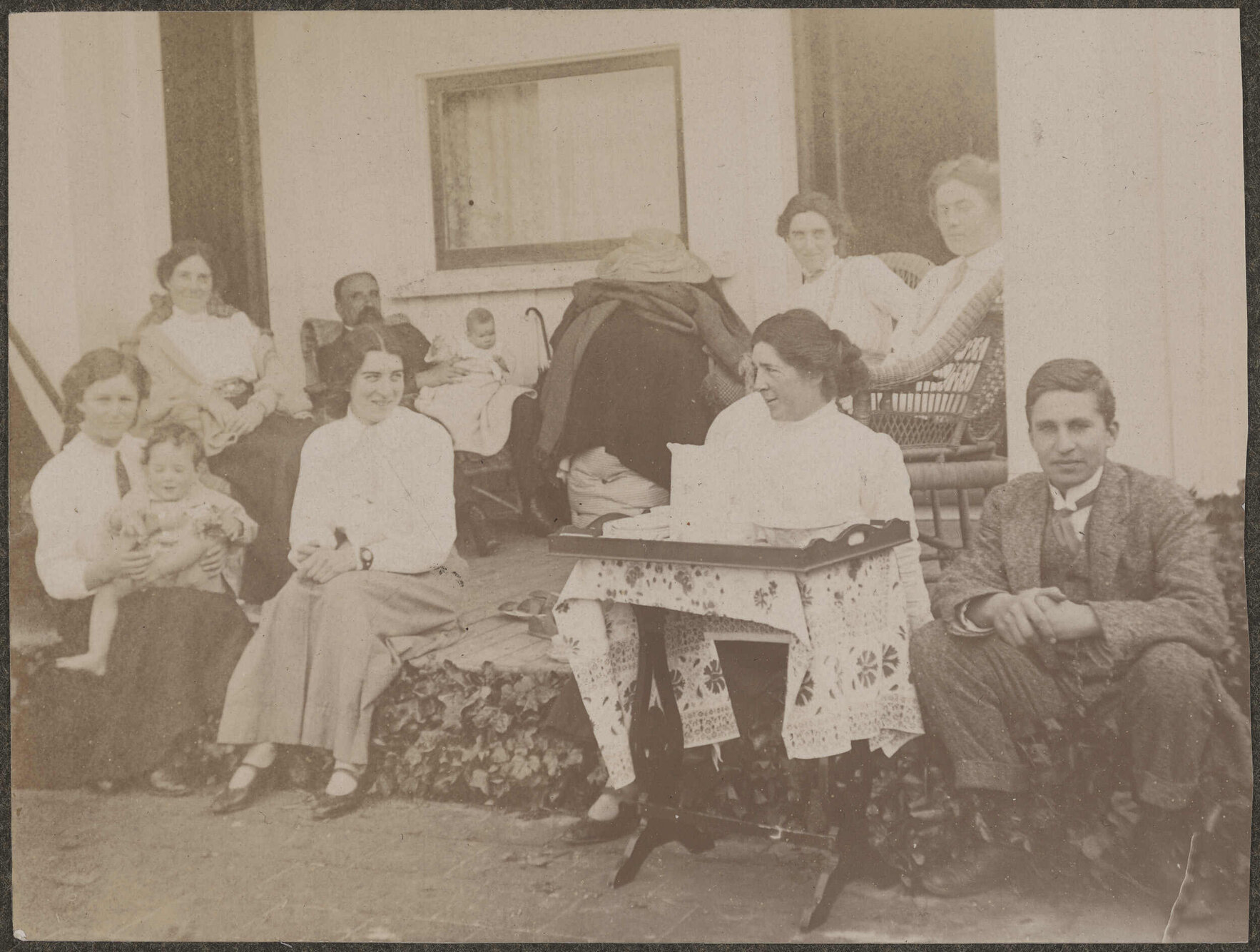Family group sitting on a deck, with table and tea tray in foreground
