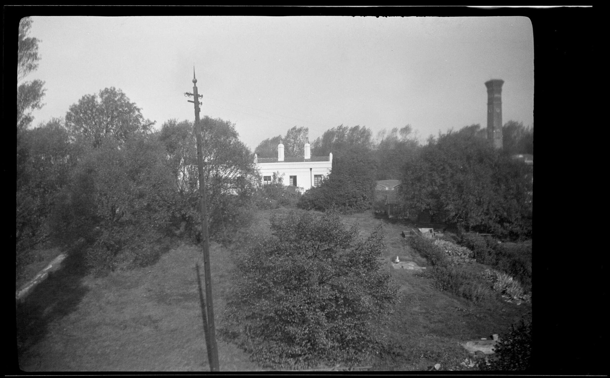 View over garden towards building and tall chimney