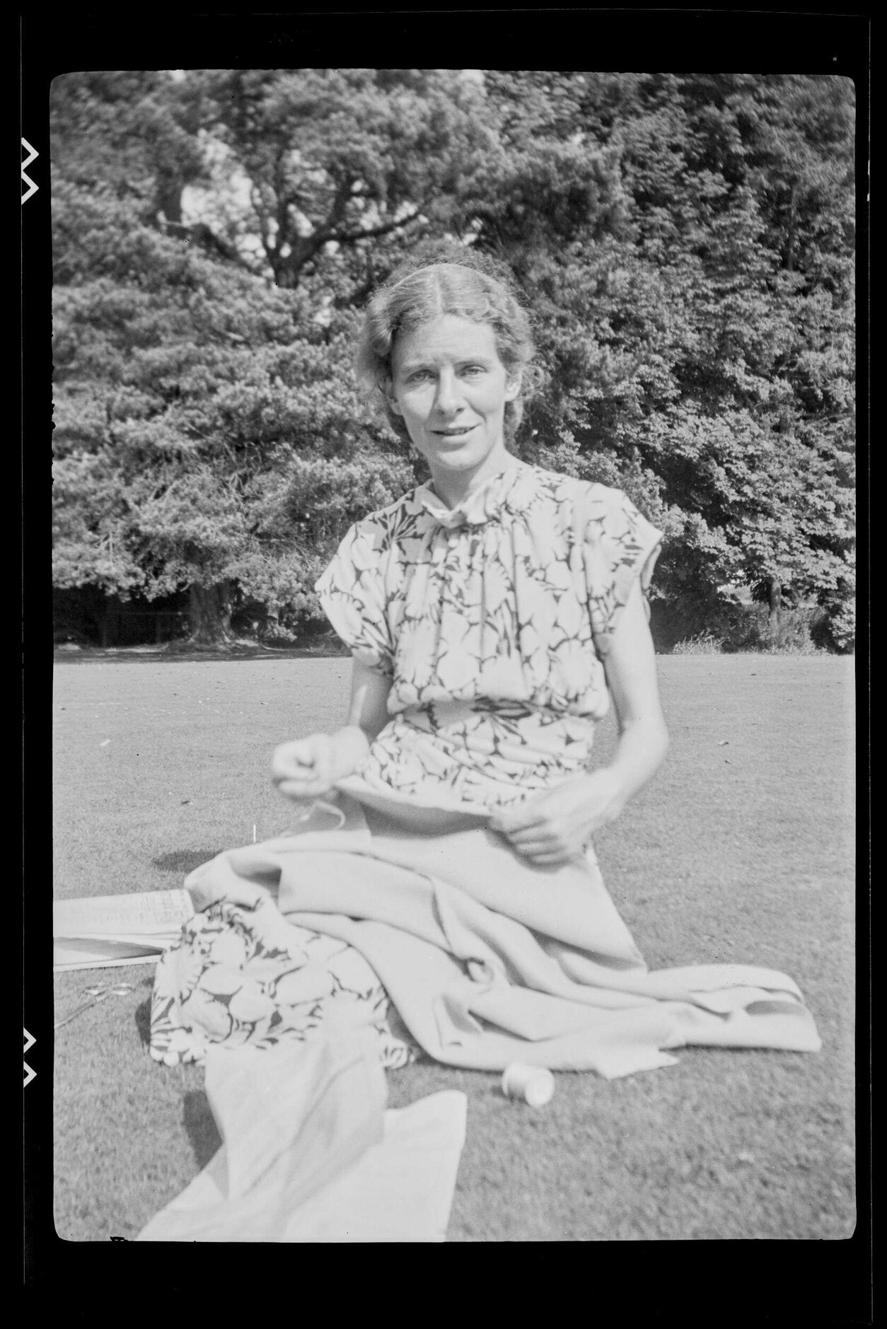 Woman sitting on grass with sewing