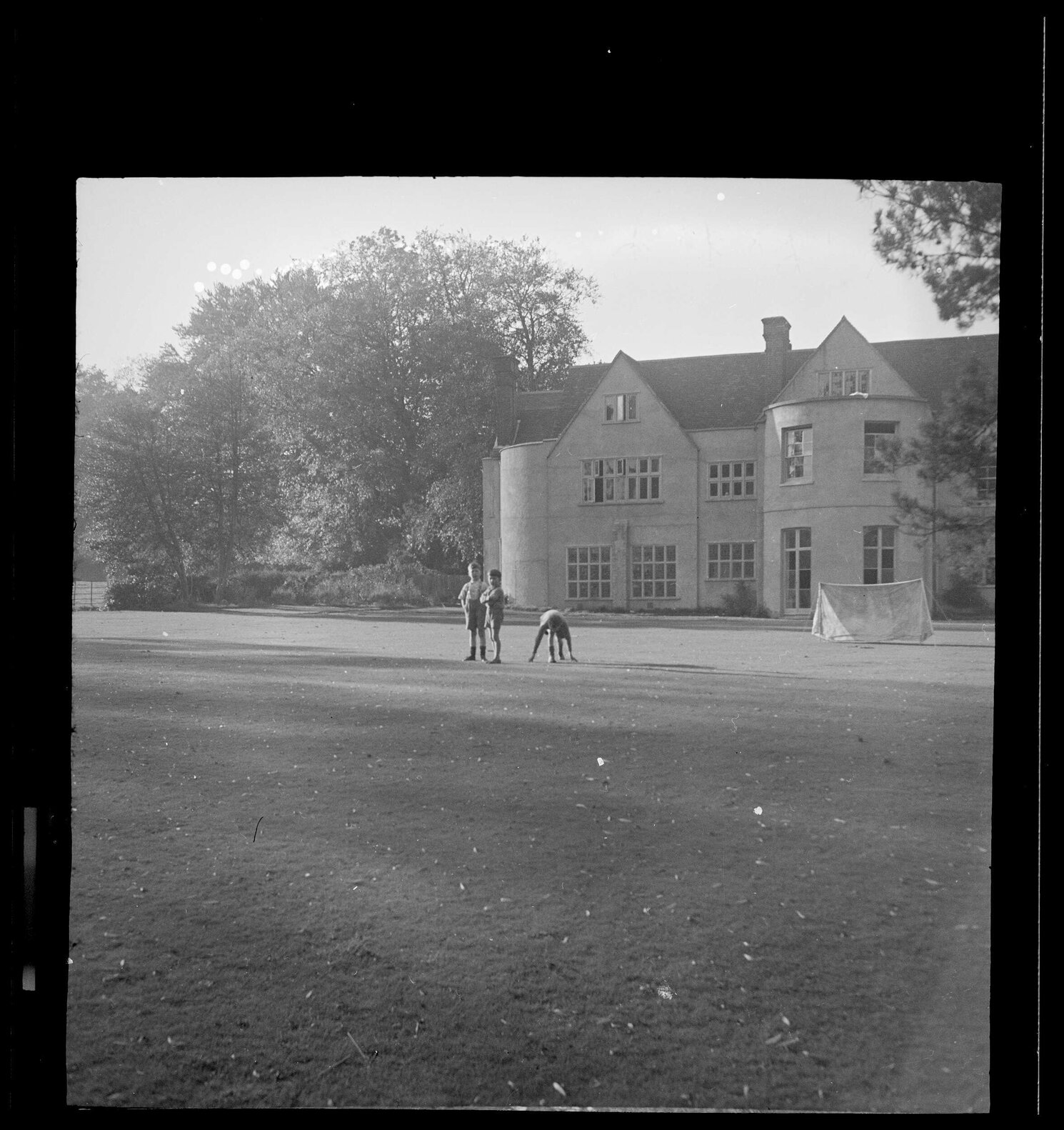 Robert, Michael, Vernon on lawn in front of buildings at Abbey School
