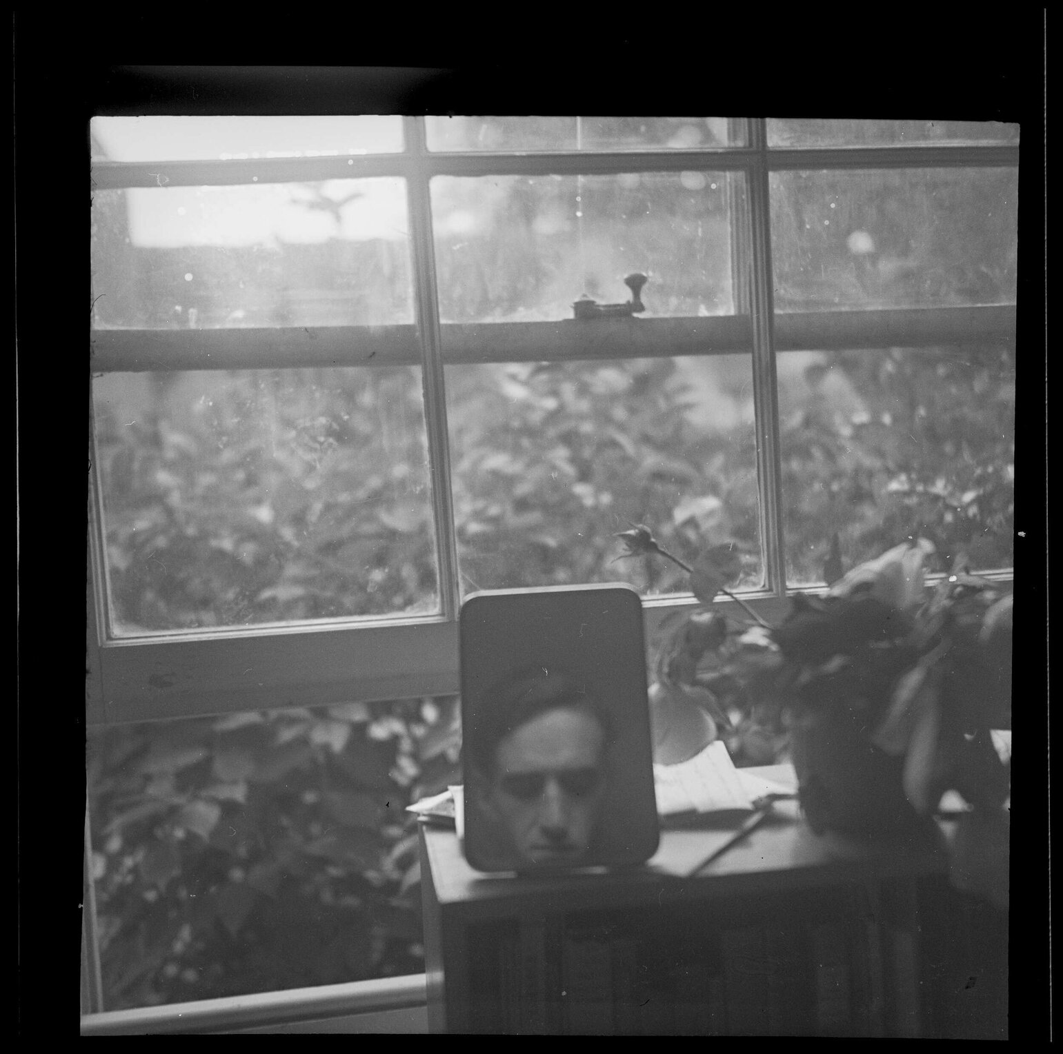 Mirror with reflection of Charles Brasch in front of an open window