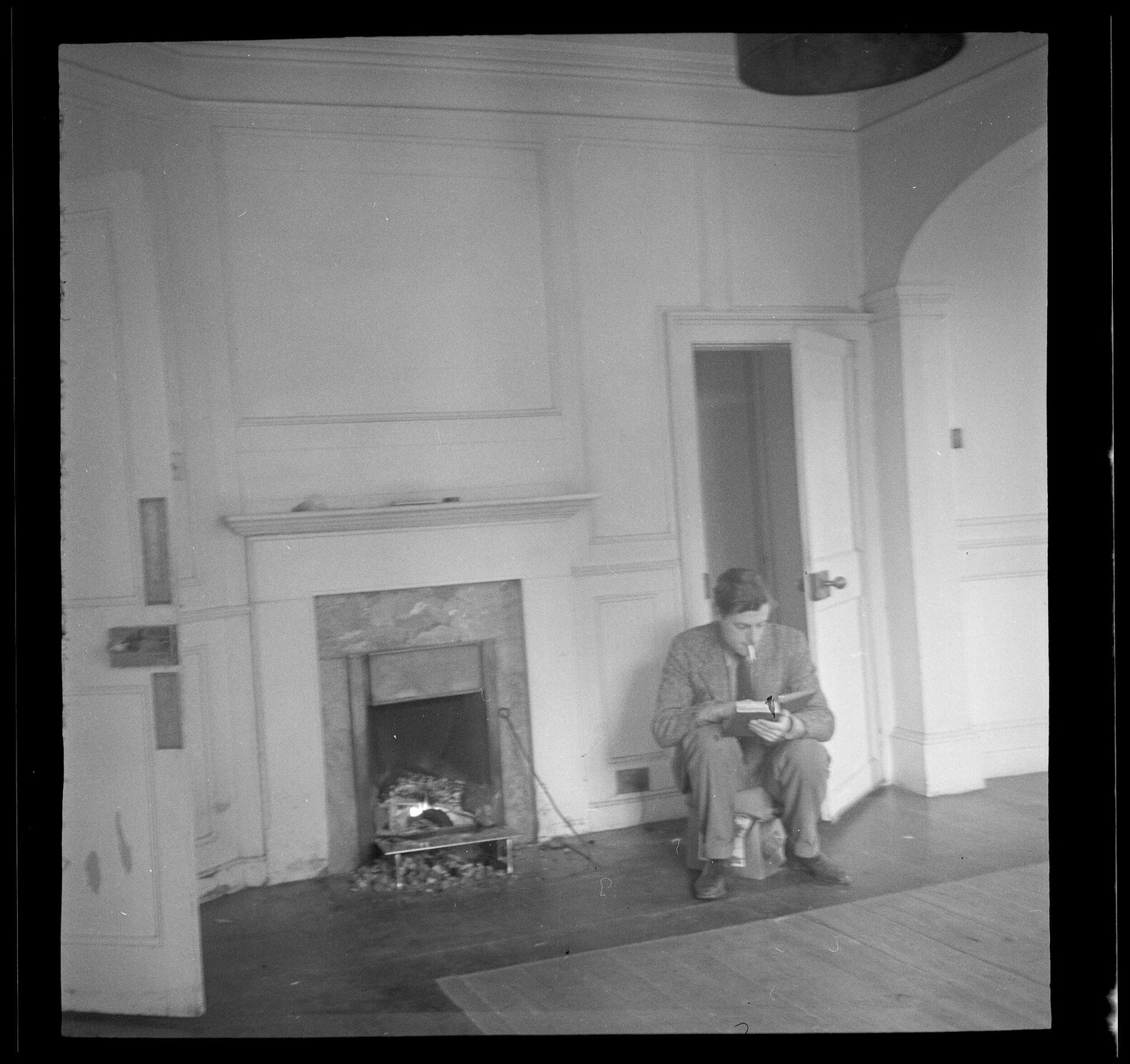 Man sitting by a fireplace reading [Roger Cox]