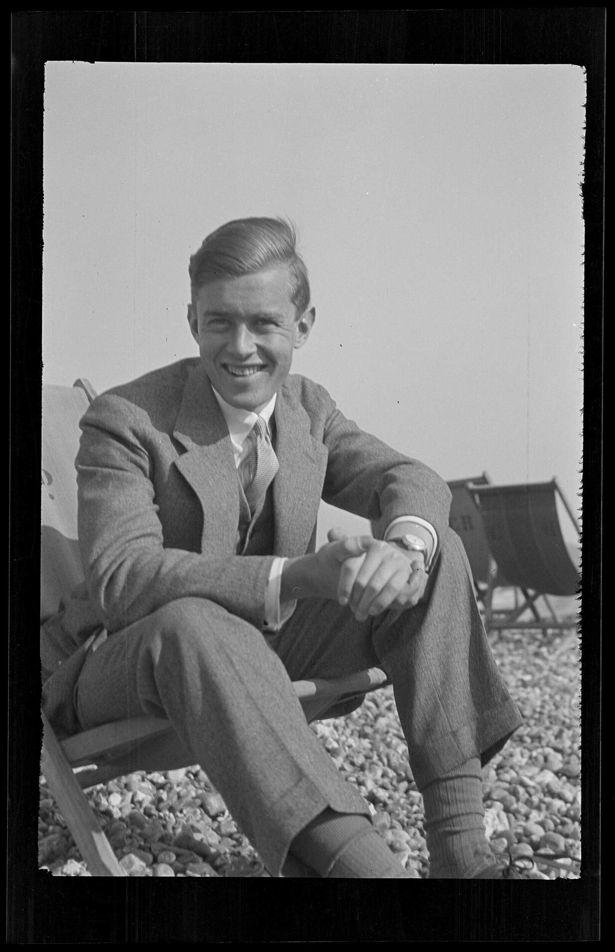 Unidentified man on a deck chair on a stony beach