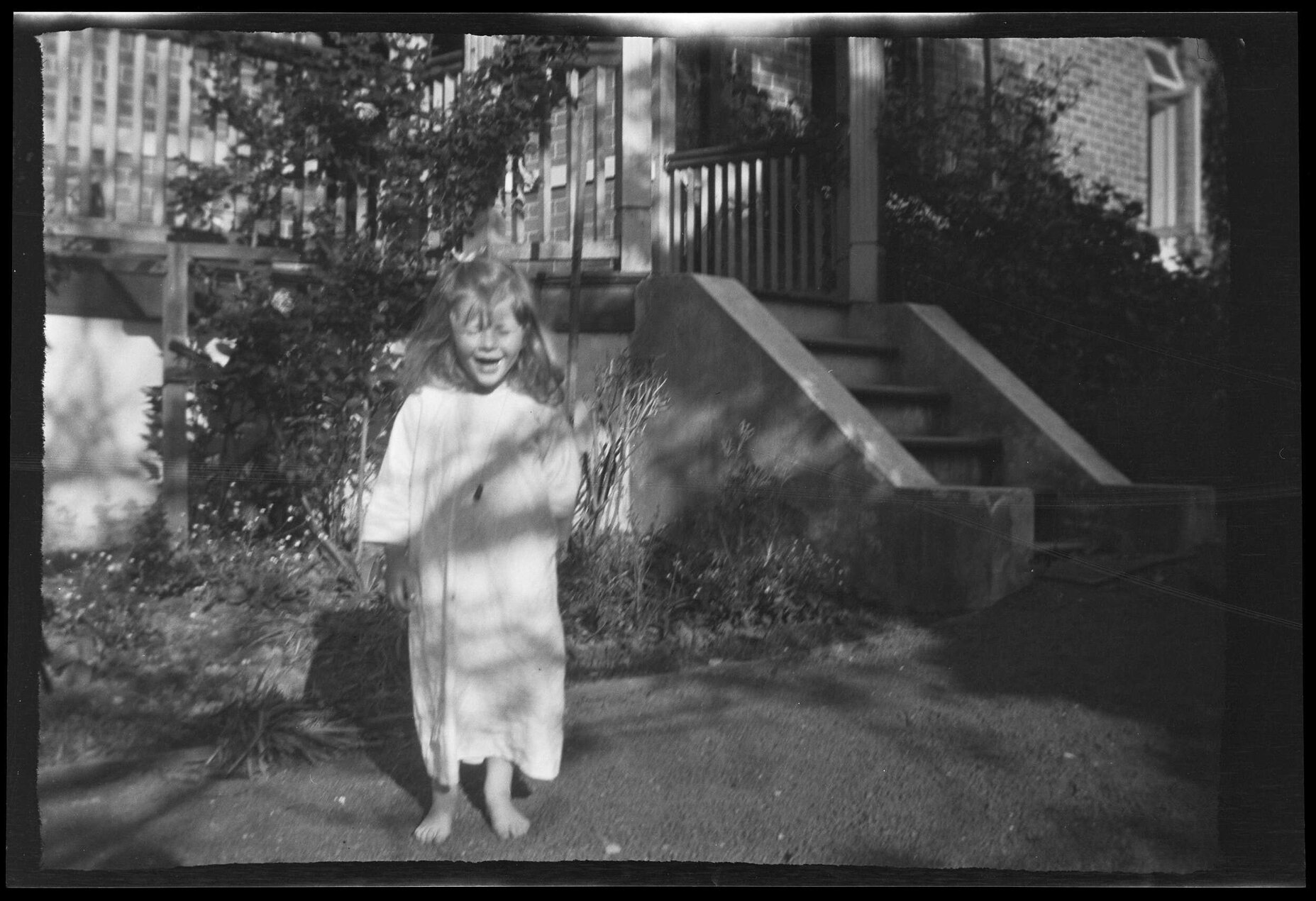 Bare-footed girl wearing a smock, standing in a garden