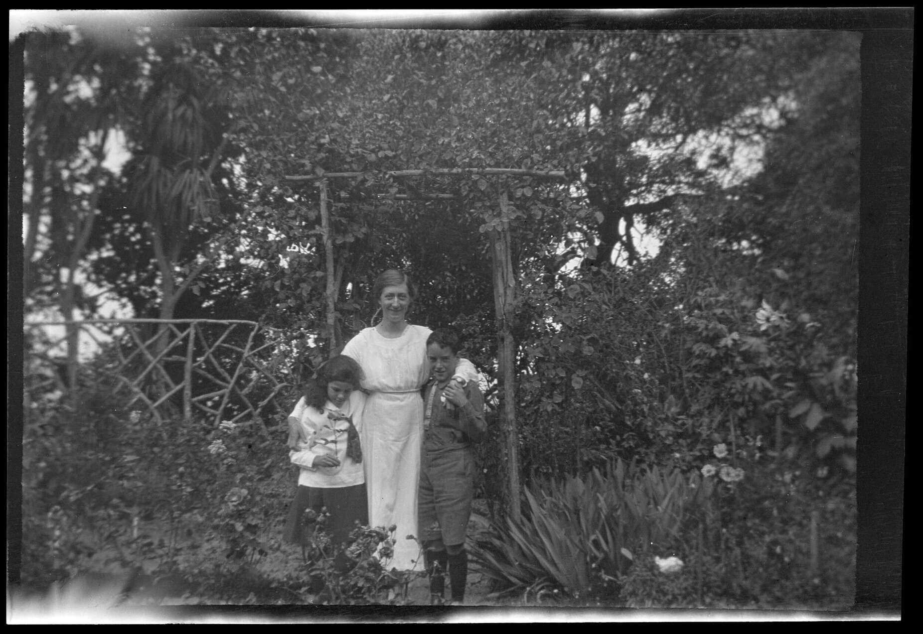 Unidentified woman with a girl and a boy, standing in a garden