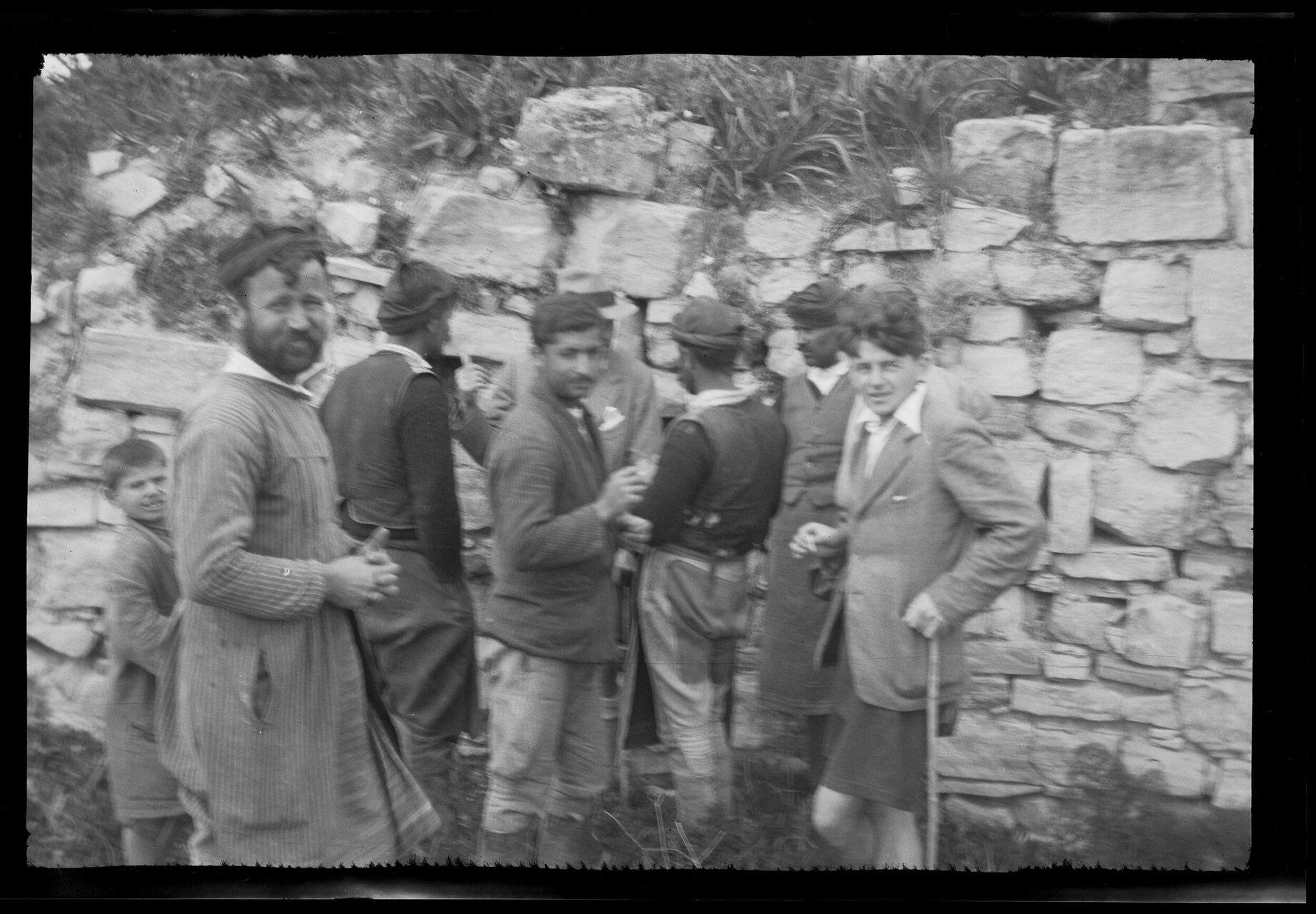 Group of men and boys next to stone wall