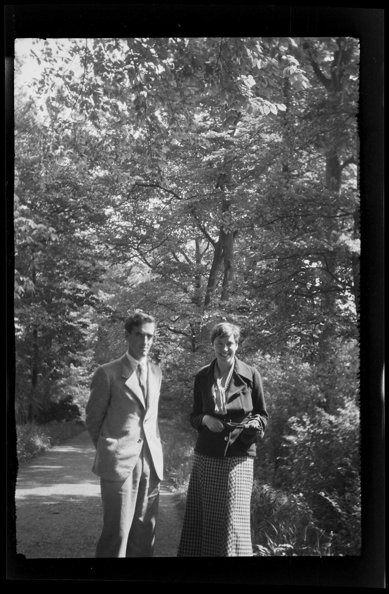 Charles Brasch and unidentified woman on a tree-lined road