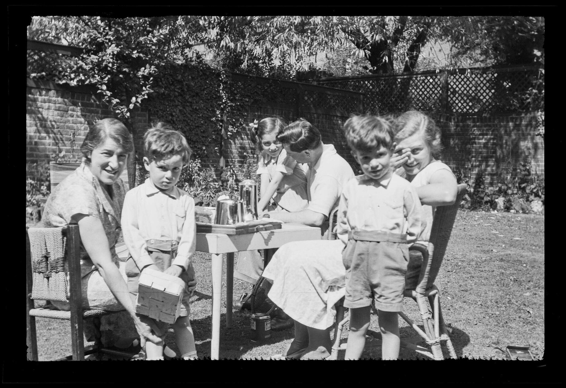 Group of children and adults at a table in a domestic garden