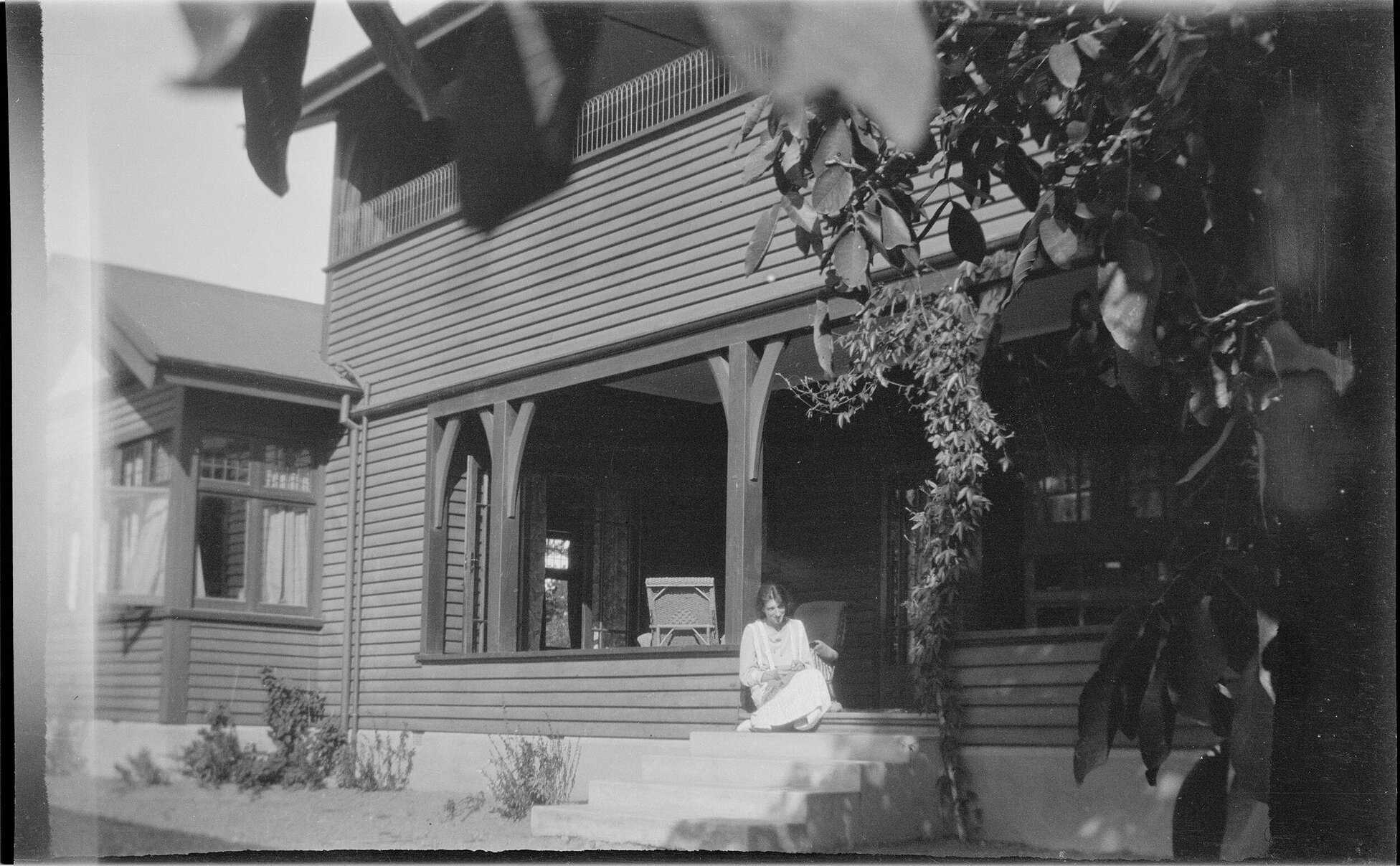 Two-storey house and woman sitting on step