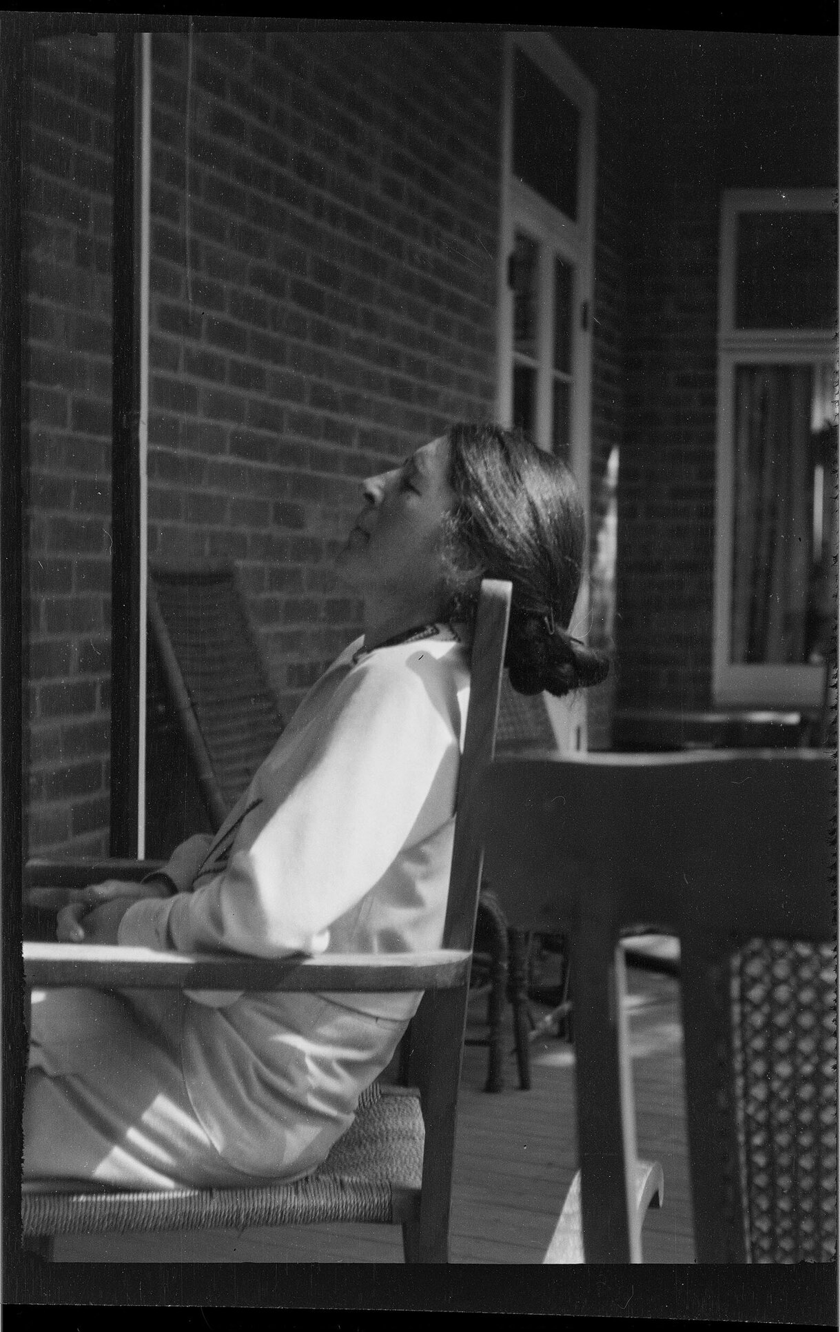 Woman sitting on the vernadah at Manono, with her head back and eyes closed