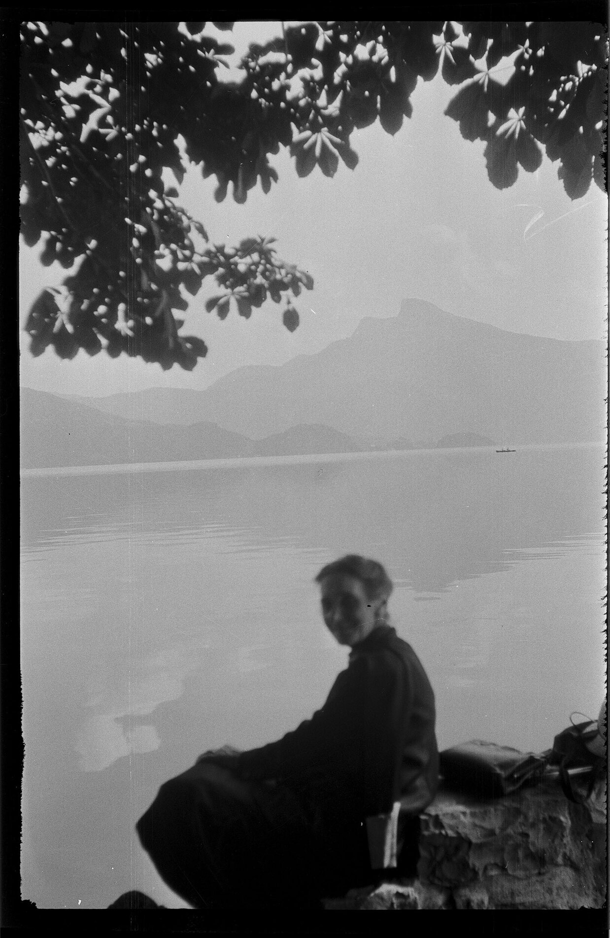 Woman sitting on a shore, with a mountain in the distance