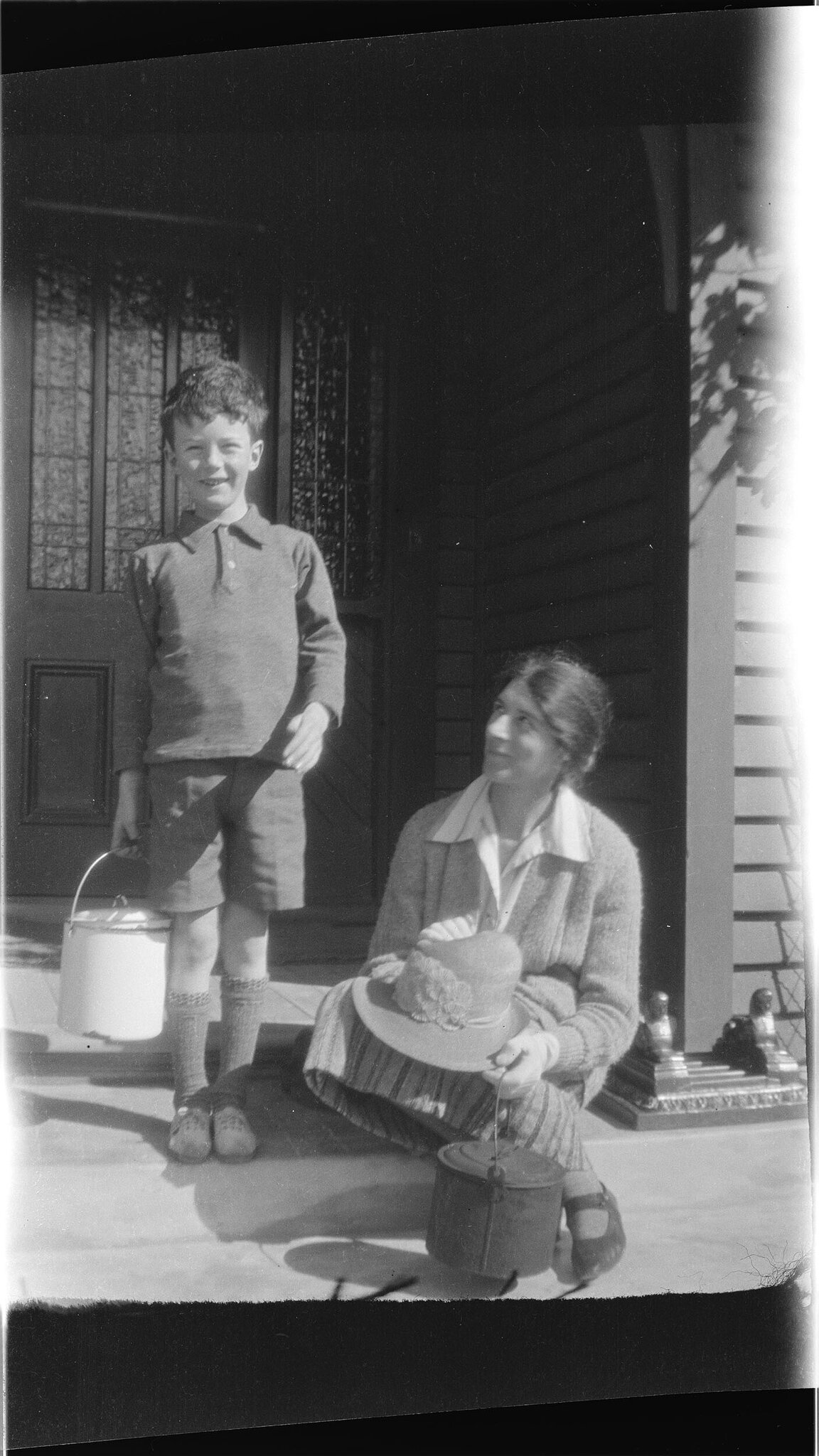 Boy and woman on a doorstep, carrying billies