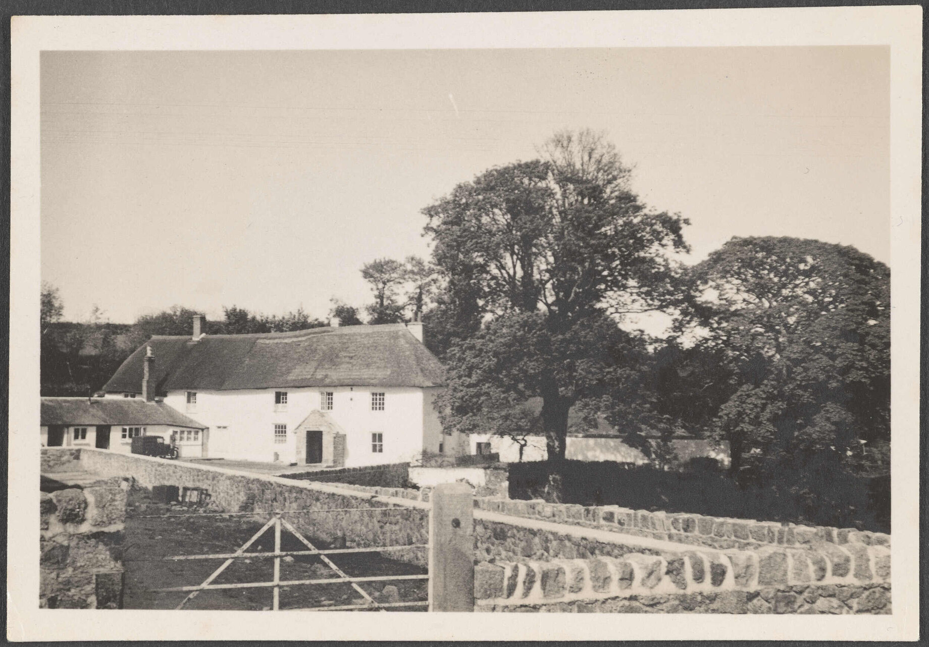 Thatched house, trees, and stone walls