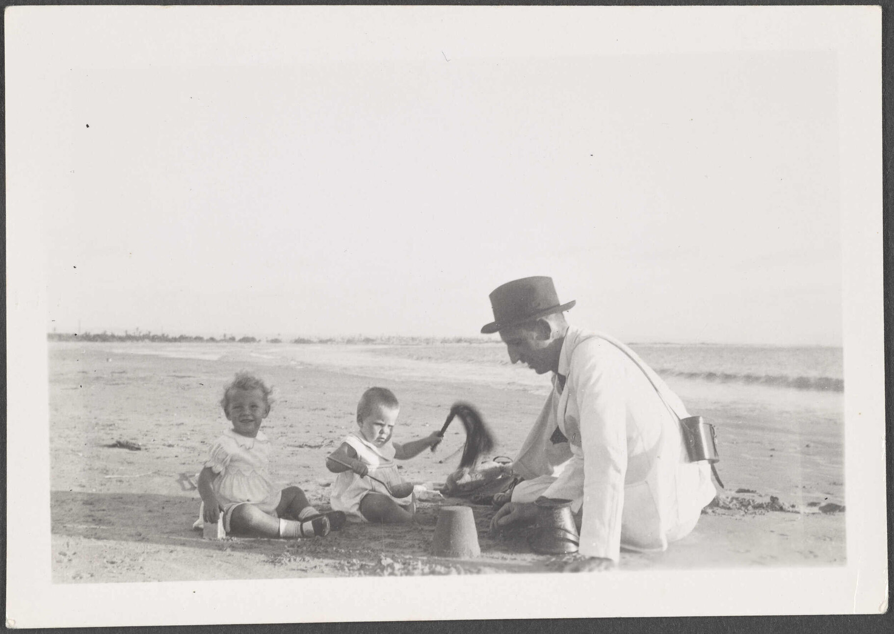 Unknown man and two children playing on a beach