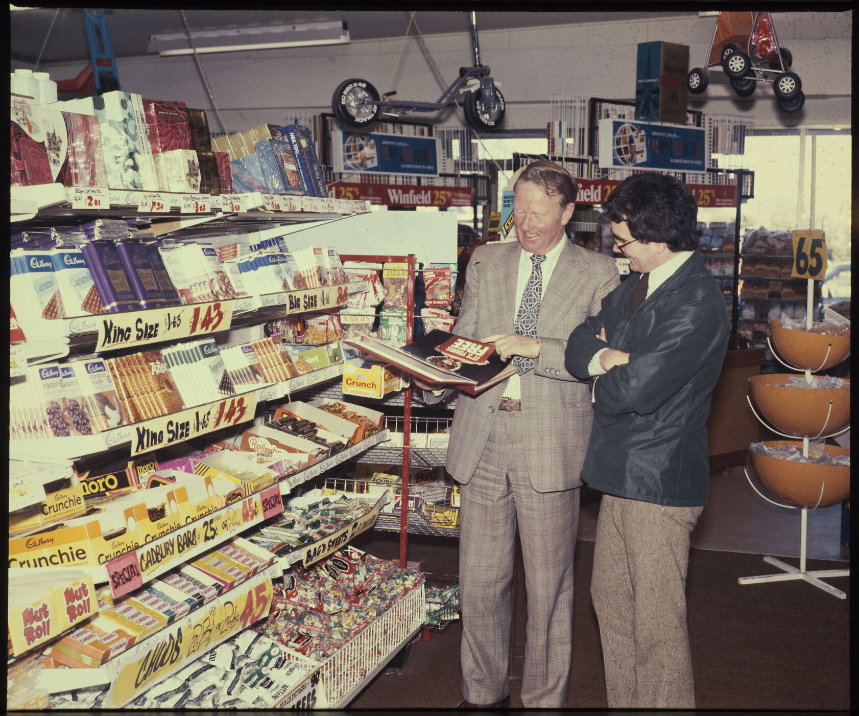 Two men standing next to a Cadbury display stand