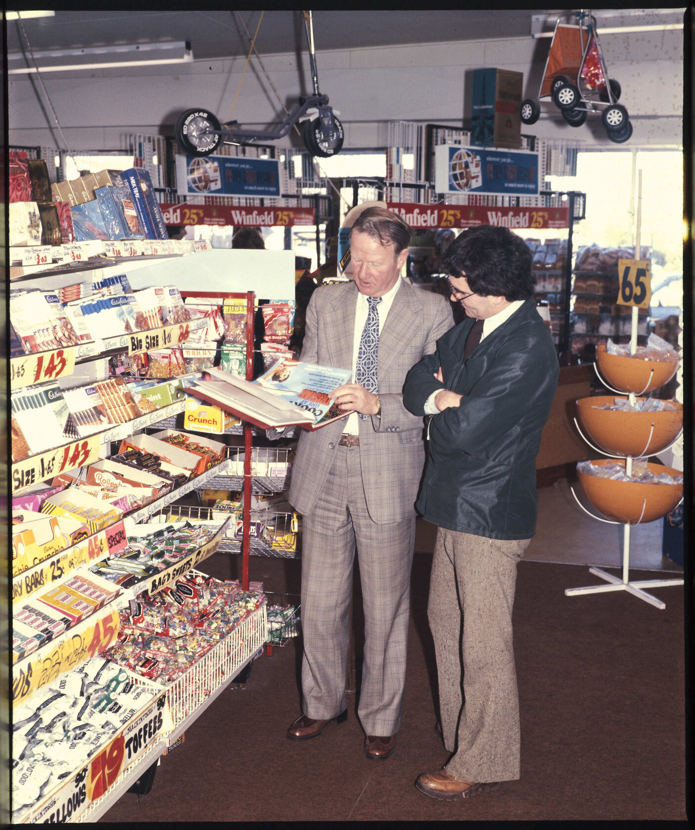 Two men standing next to a Cadbury display stand