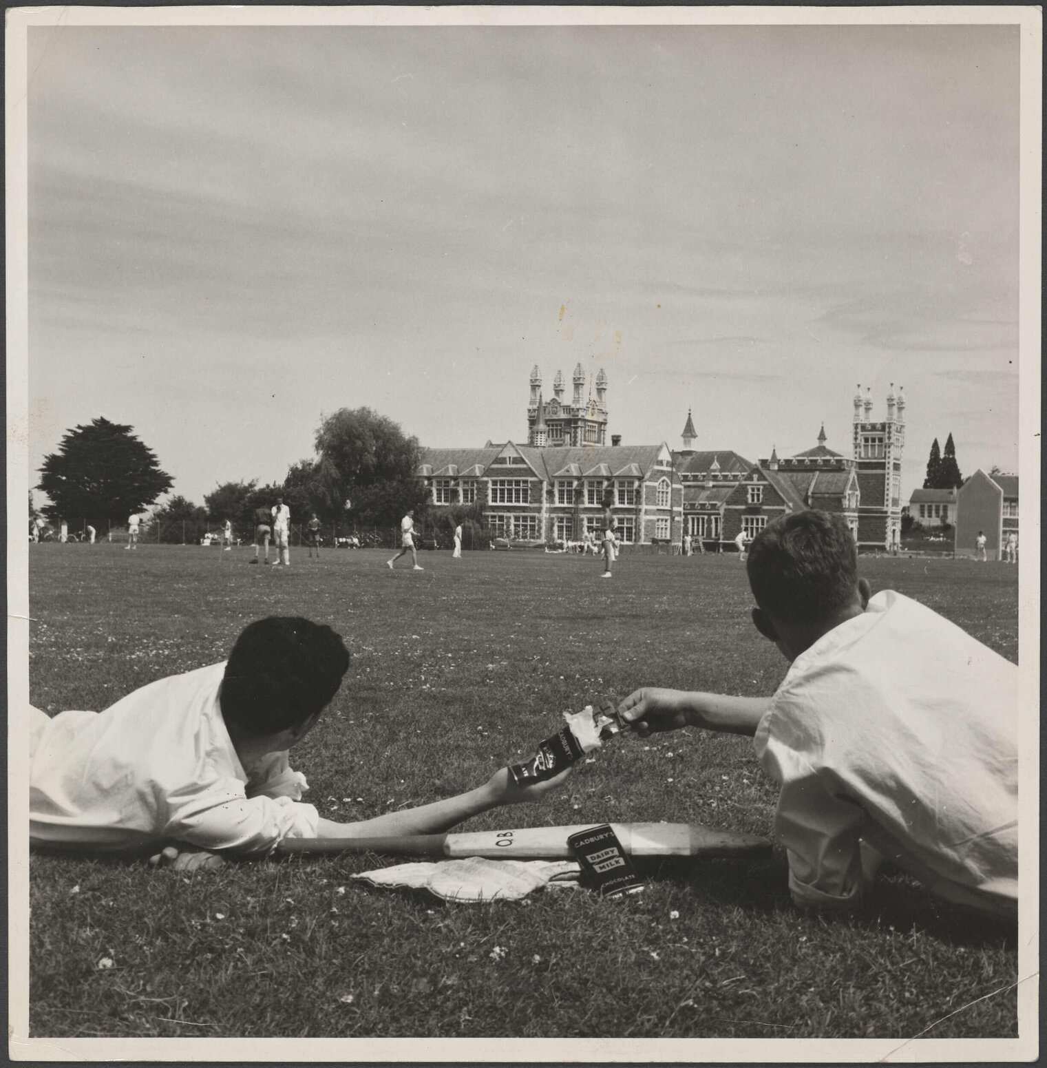 Two boys with Cadbury Dairy Milk chocolate on Otago Boys' High School playing field