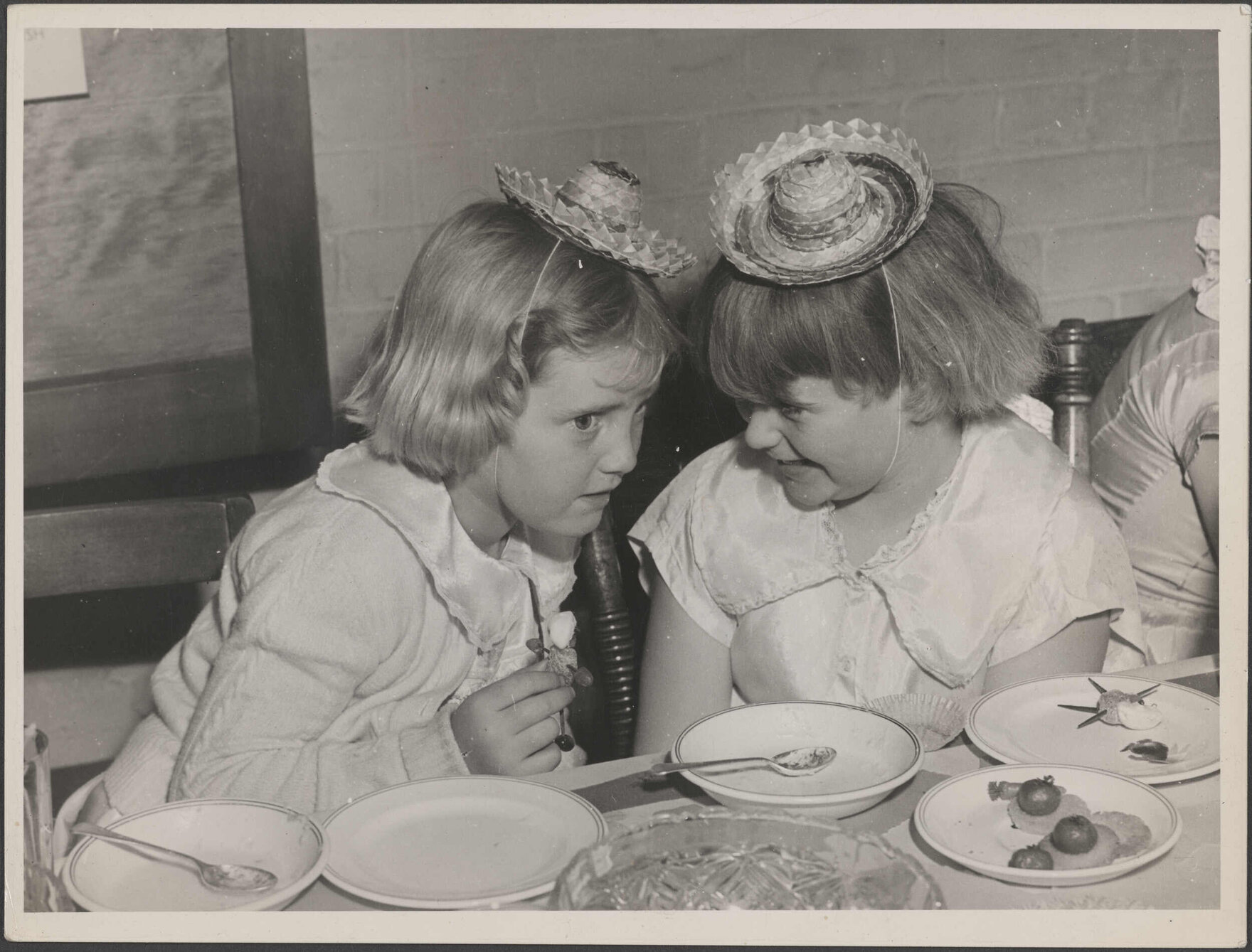 Two young girls with party hats and food