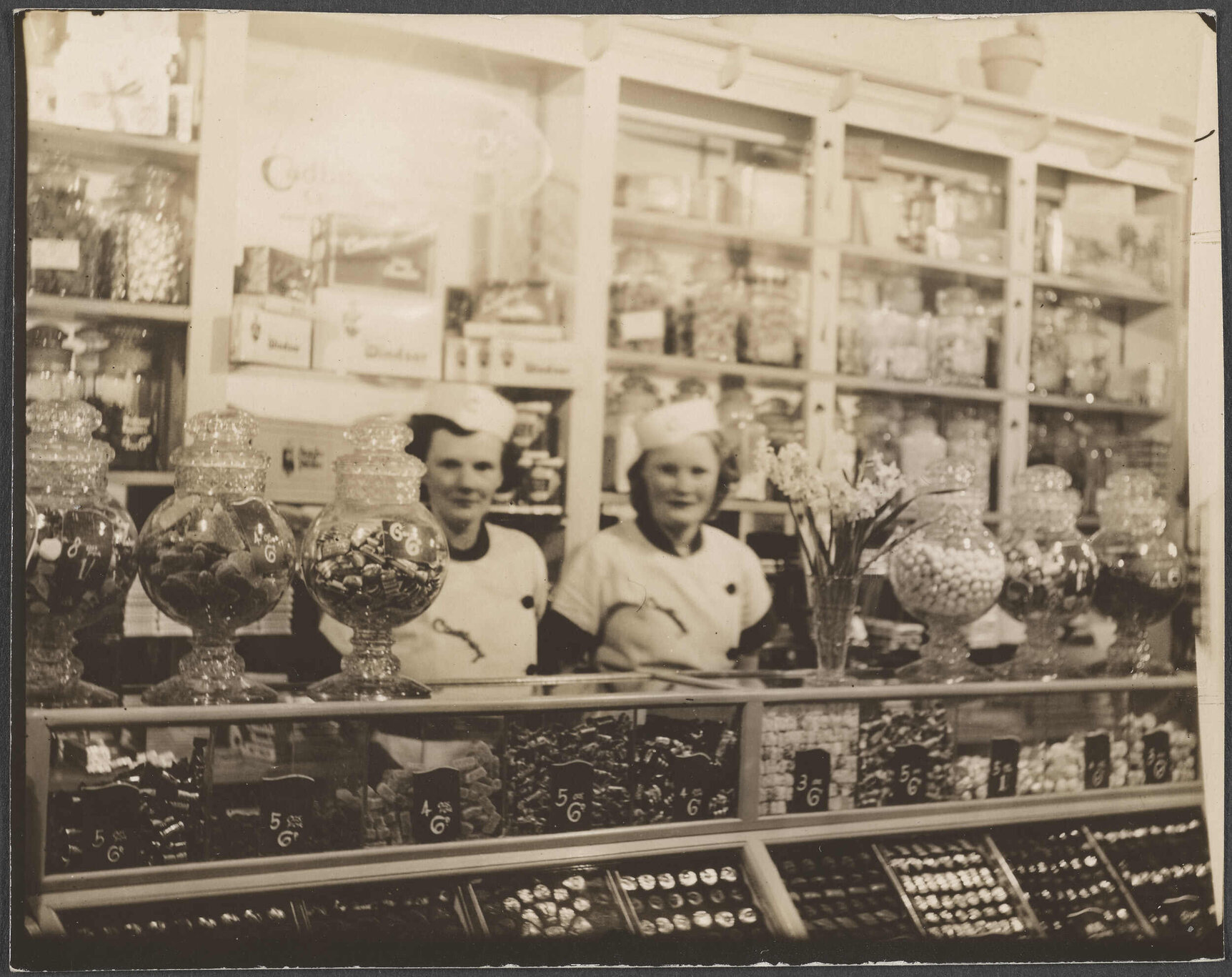 Two women wearing Cadbury uniforms, behind a shop counter