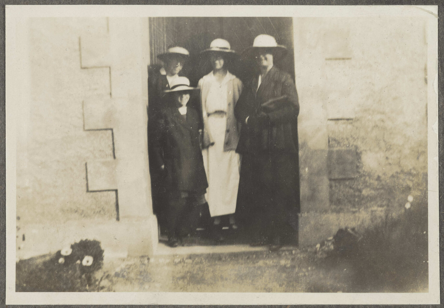 Four unidentified people standing in doorway of building