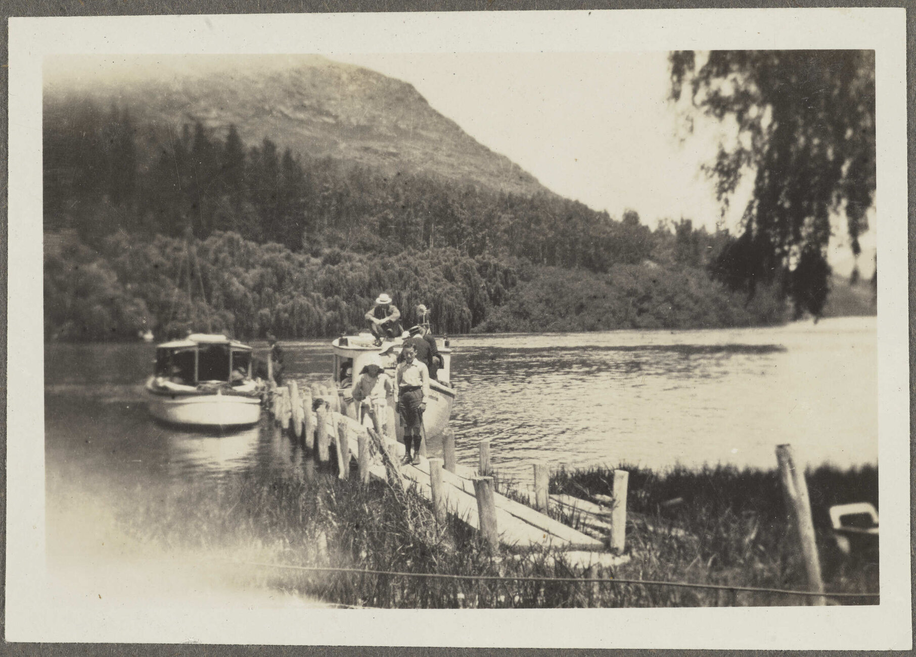 Charles [and Lesley] Brasch standing in front of boats on pier