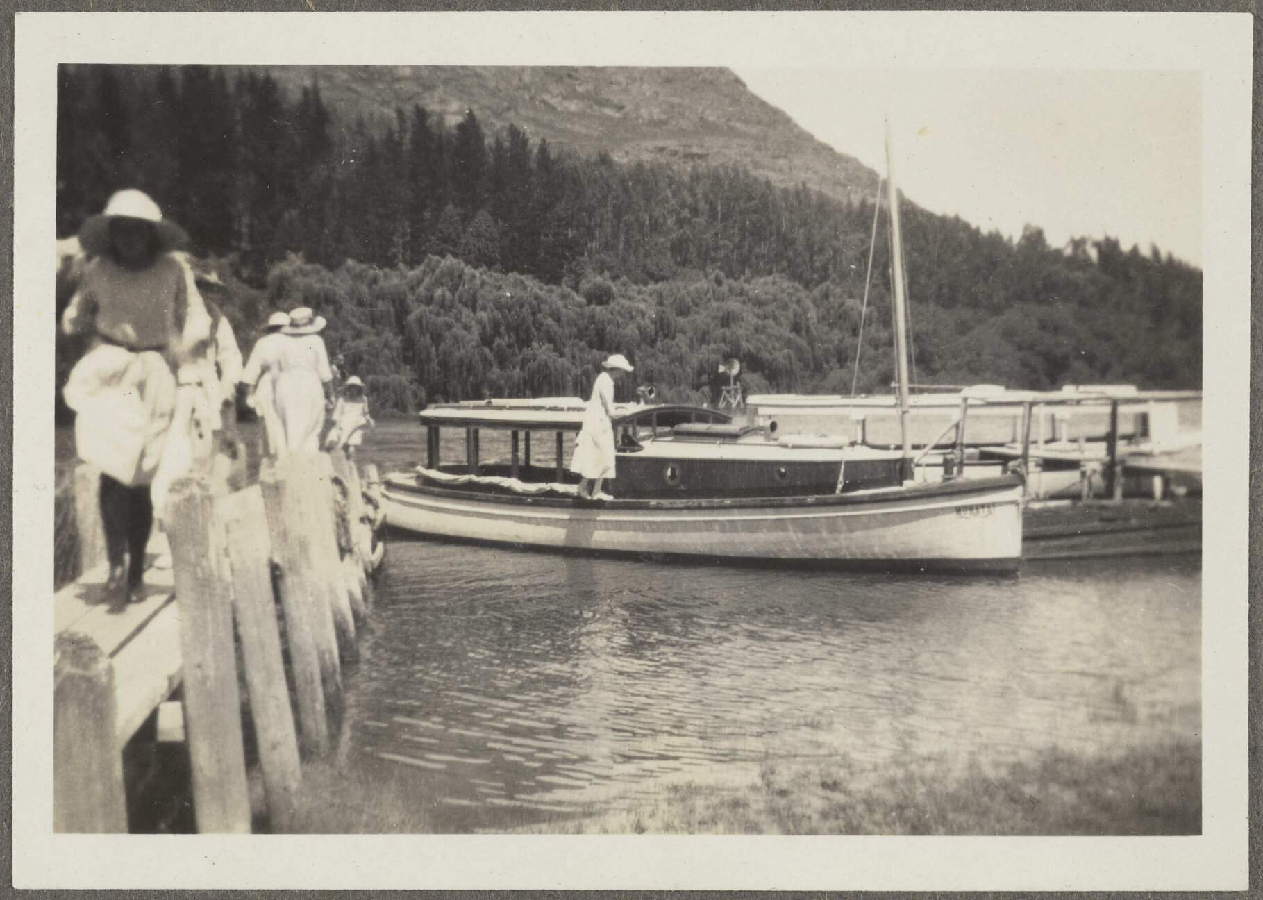 Unidentified girl standing on a boat and five unidentified people walking up pier