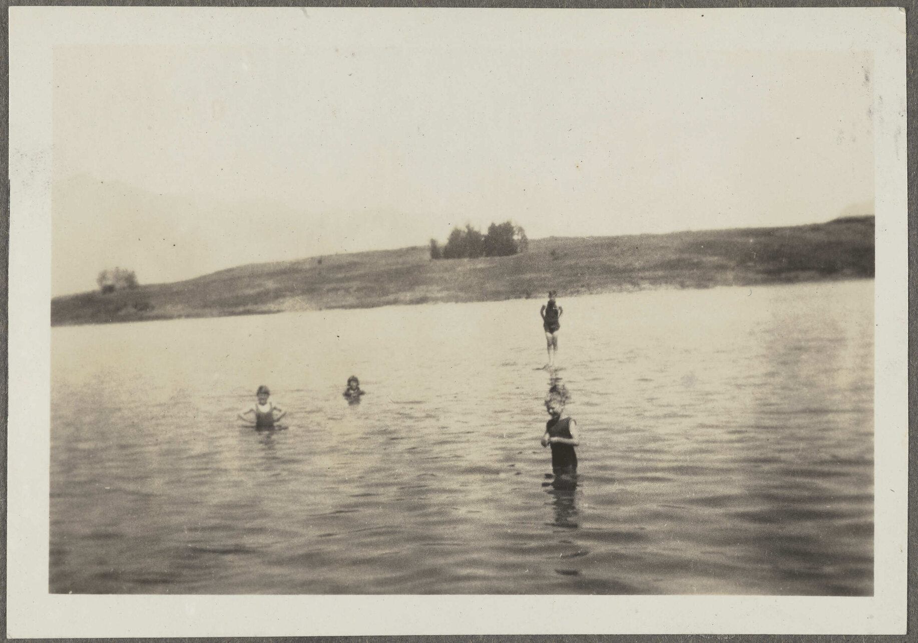 Four unidentified children standing in lake