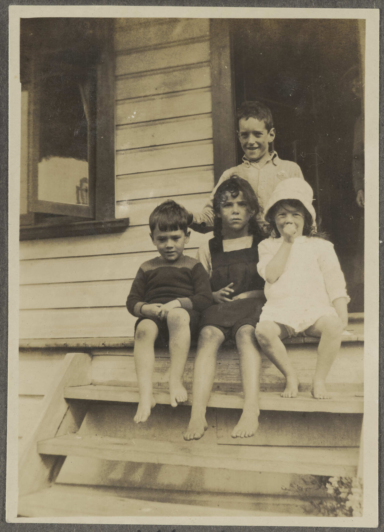 Charles and Lesley Brasch and two unidentified children sitting on steps