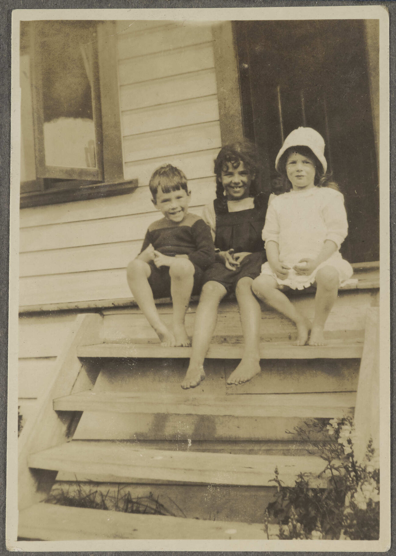 Lesley Brasch and two unidentified children sitting on steps