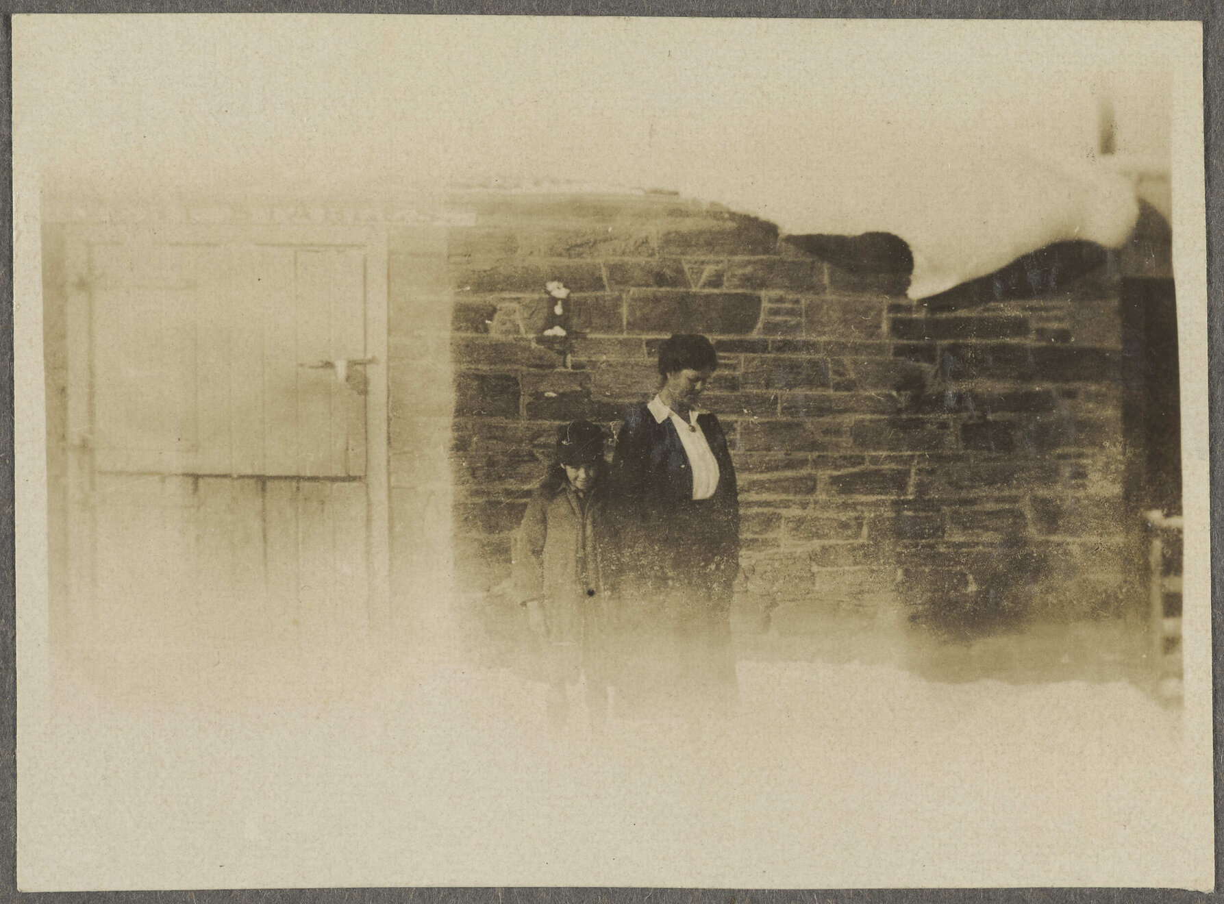 [Lesley Brasch and Jane McCartney] standing in front of stone building