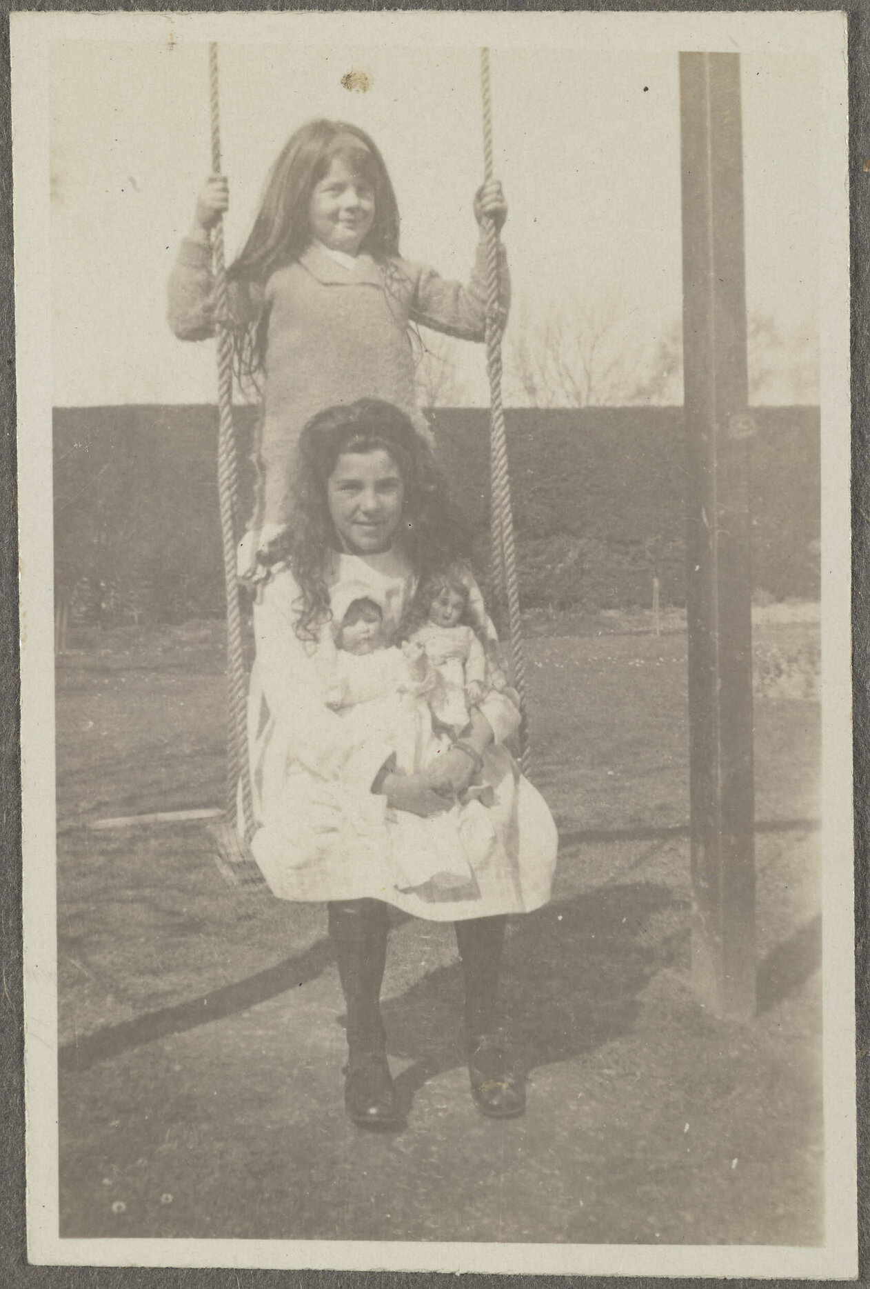 Lesley Brasch sitting on swing, with unidentified girl