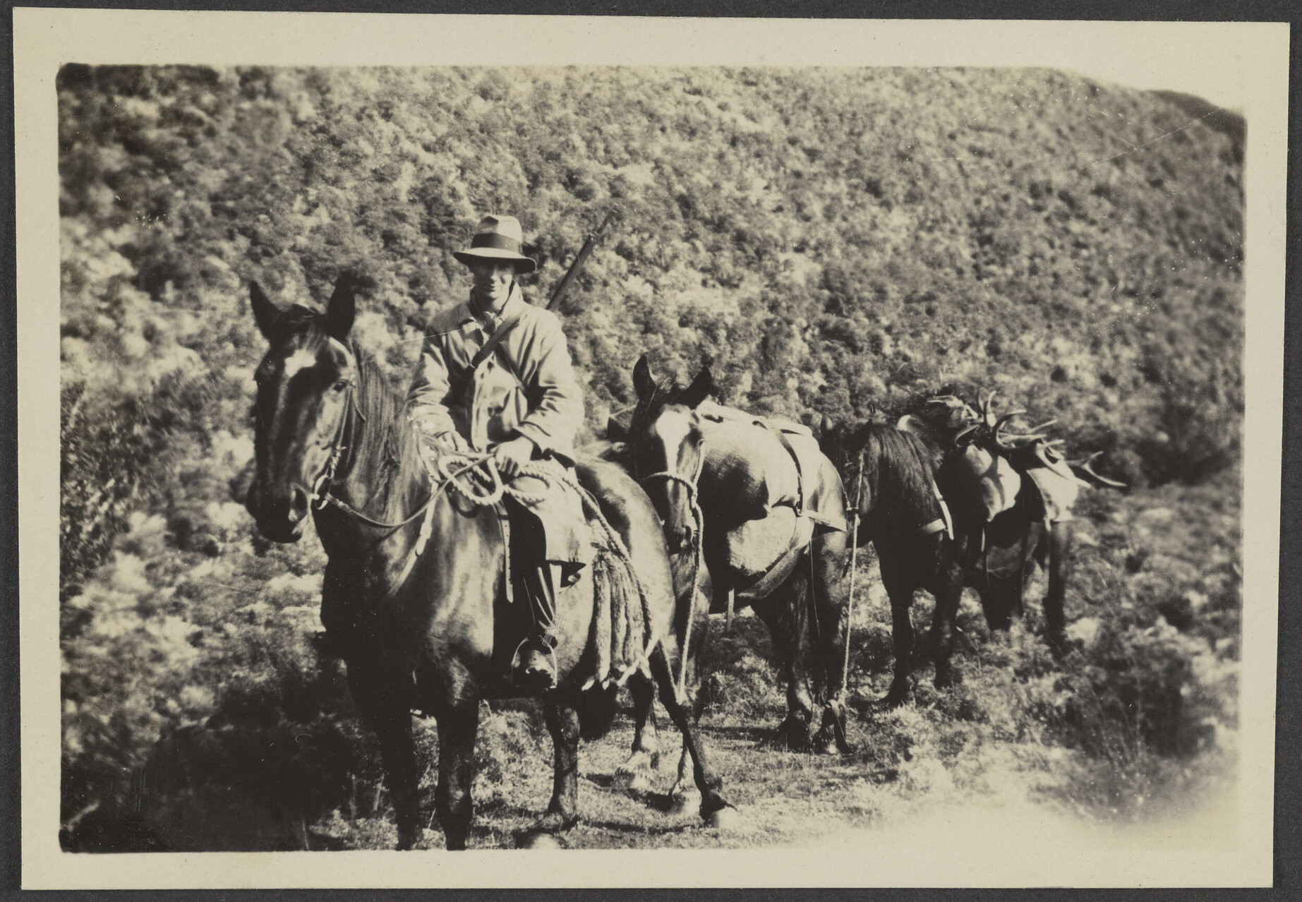 Unidentified man riding a horse, with two following carrying supplies and deer antlers