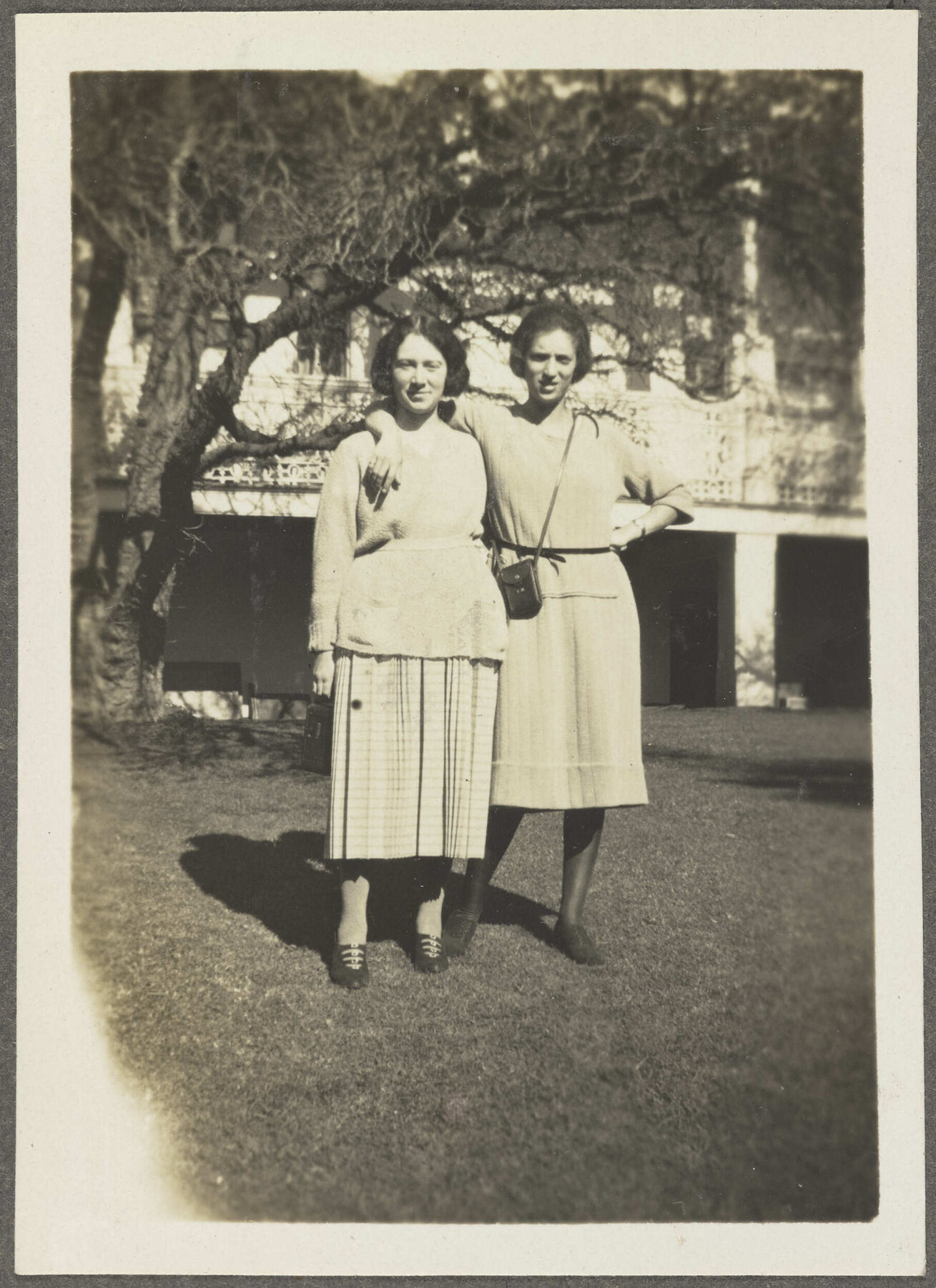 Two unidentified women standing on lawn outside house