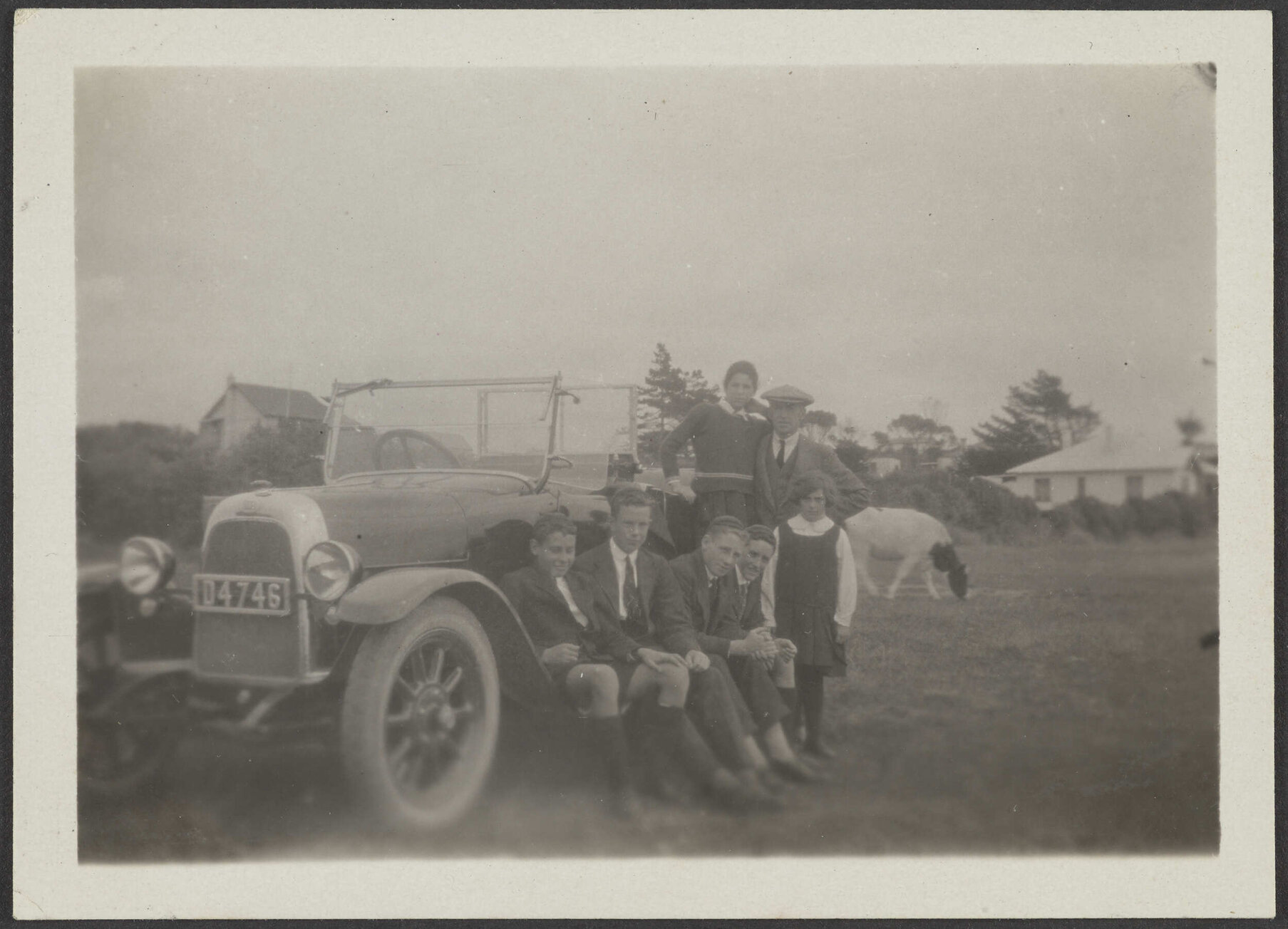 Henry, Lesley and Charles Brasch sitting around a car with four other people