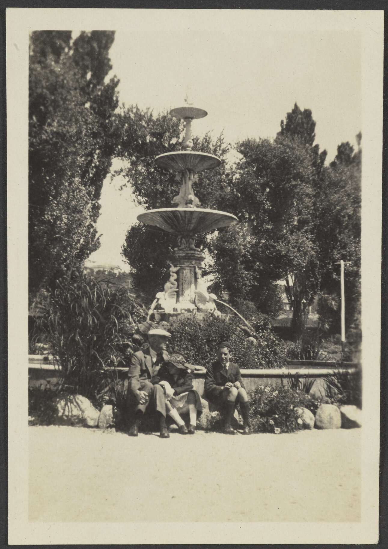 Henry, Charles and [Lesley] Brasch sitting in front of a water fountain